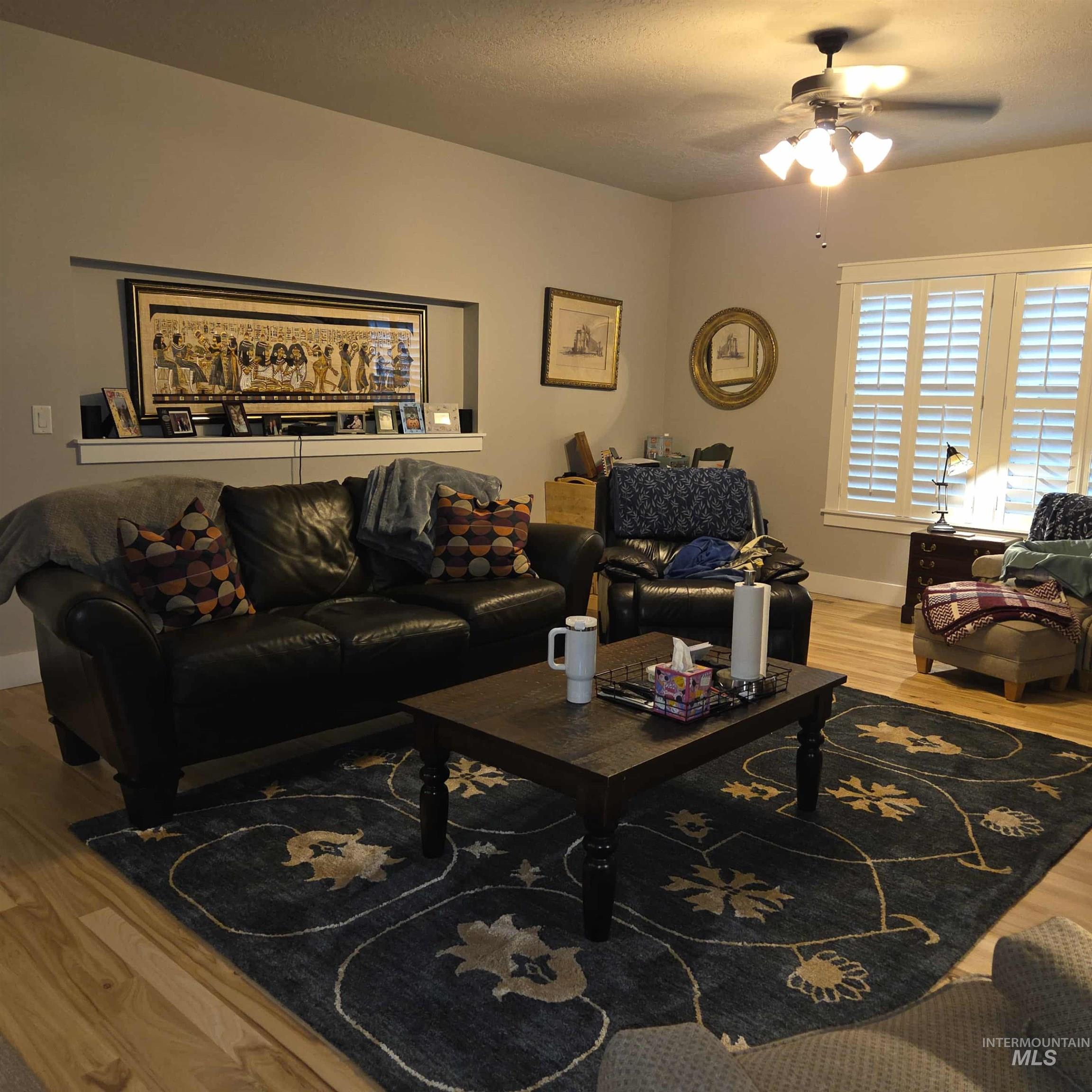 Living room featuring light wood-type flooring, ceiling fan, and a textured ceiling