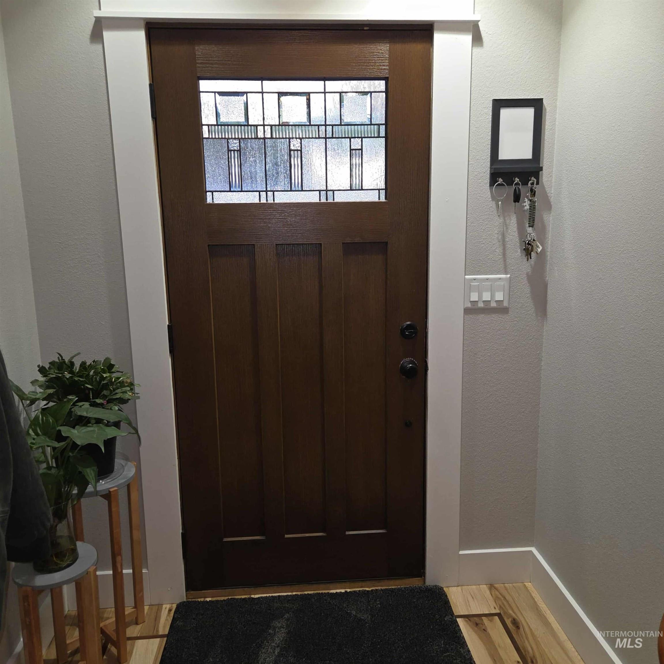 Doorway to outside with a textured wall and wood finished floors