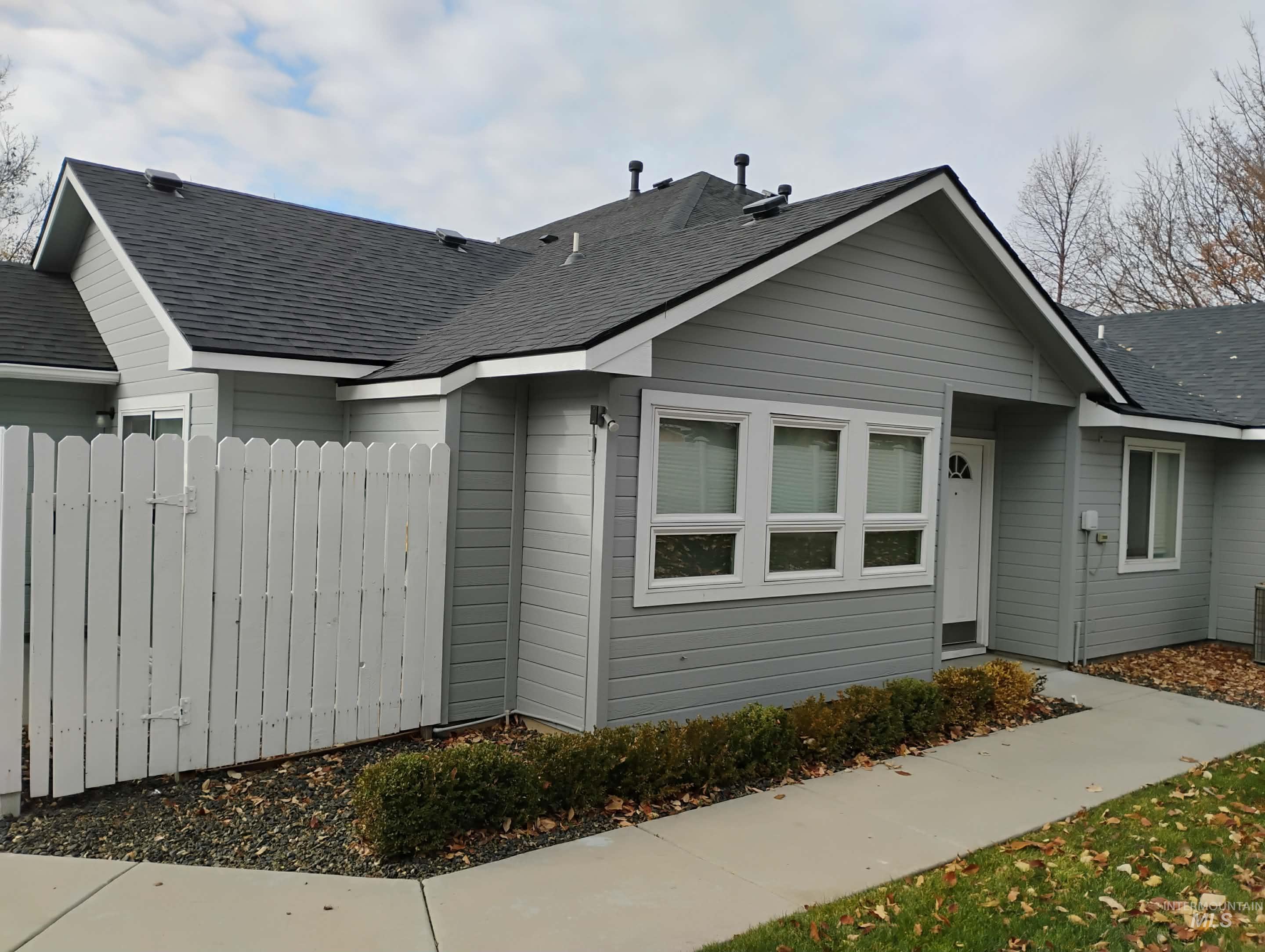 View of front of home with roof with shingles and a gate