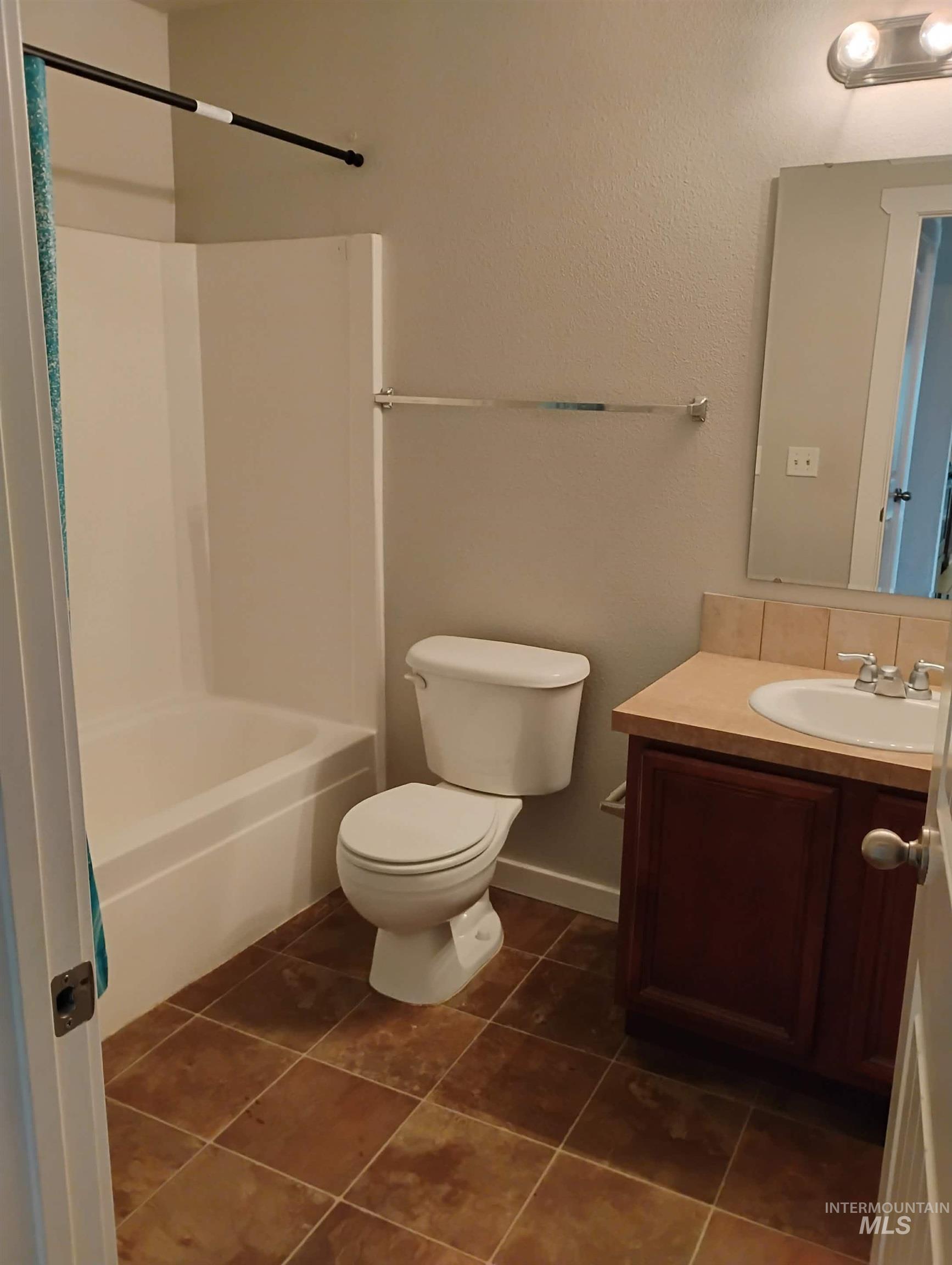 Full bathroom with vanity, dark tile patterned flooring, and shower / washtub combination