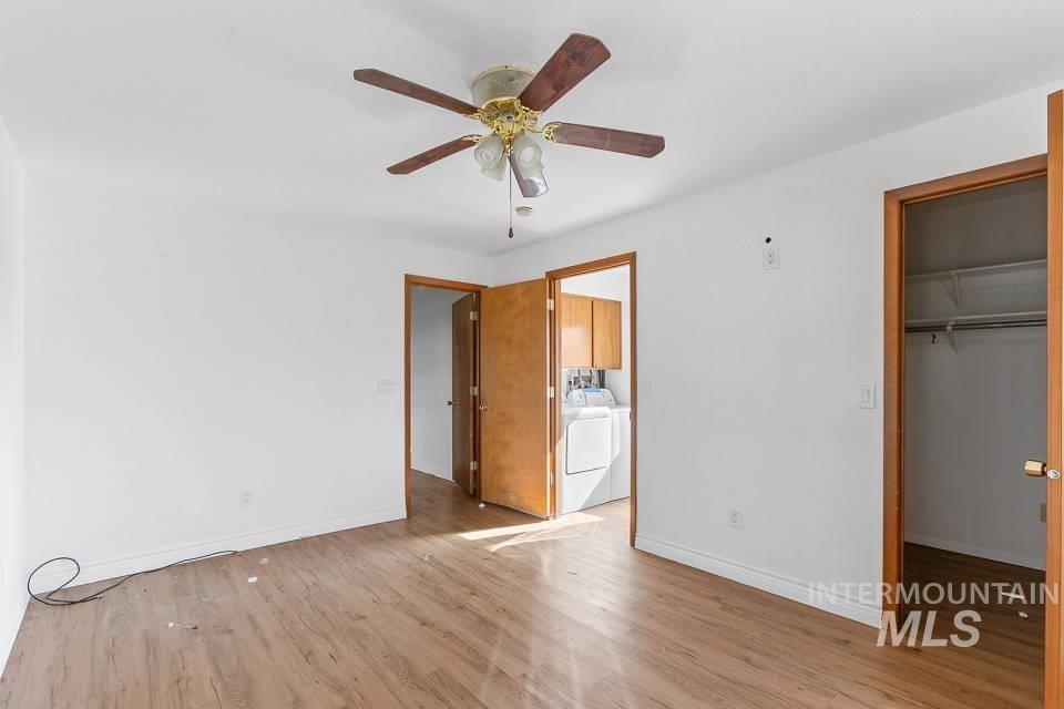 Unfurnished bedroom with light wood-style floors, a spacious closet, a ceiling fan, and washer and clothes dryer