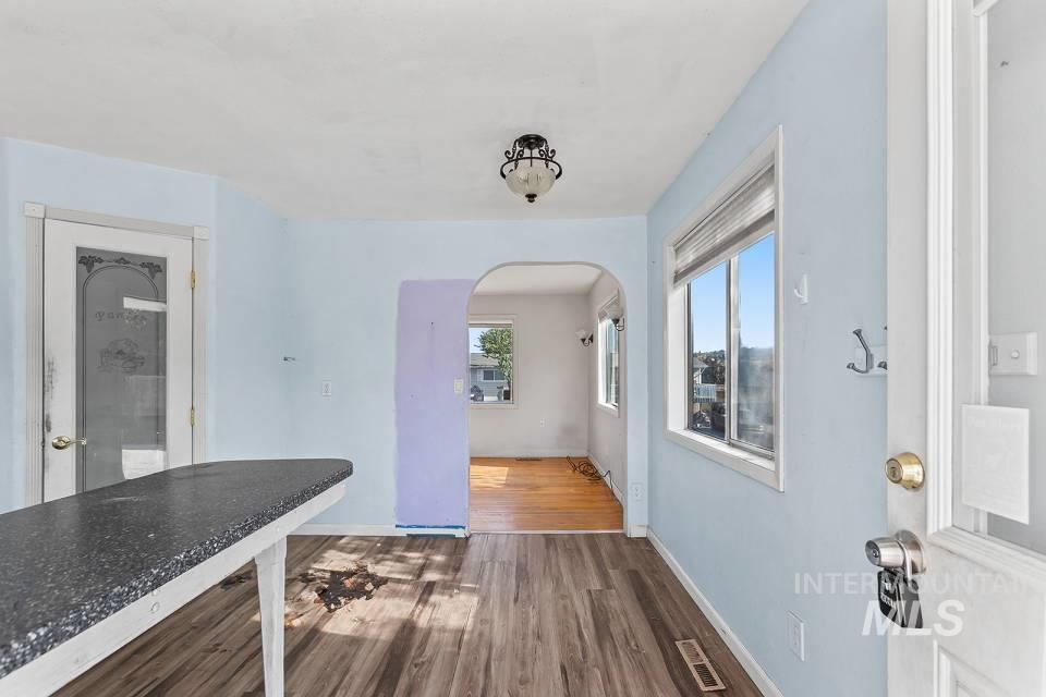 Unfurnished dining area with dark wood-style flooring and arched walkways