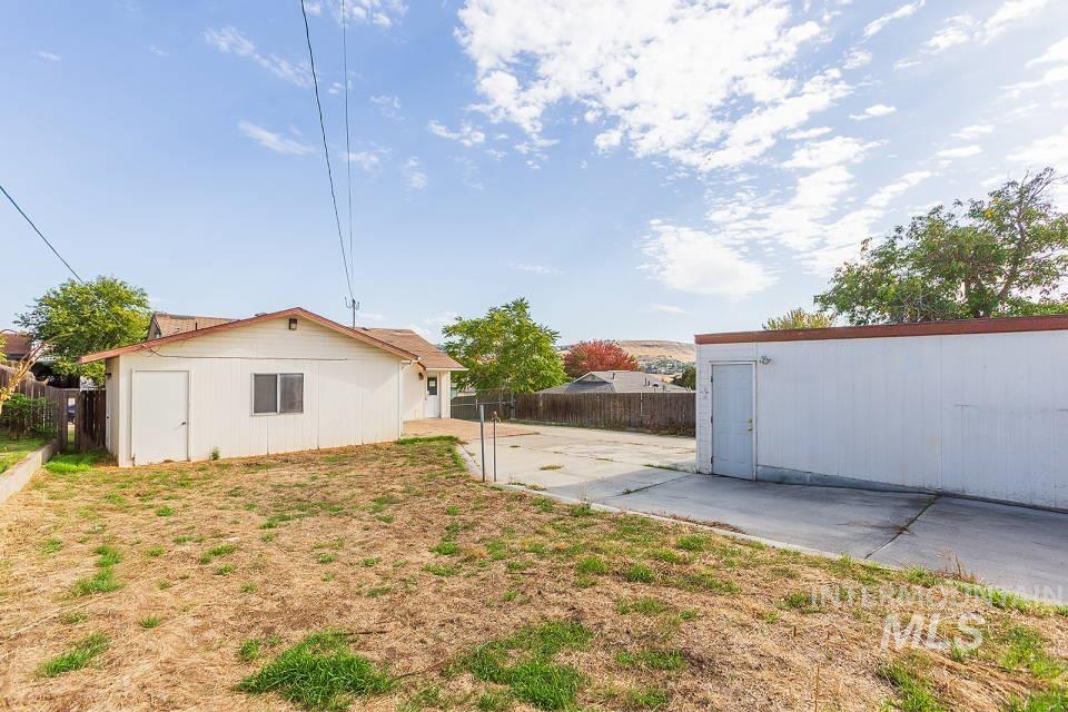 Fenced backyard featuring an outbuilding and a patio