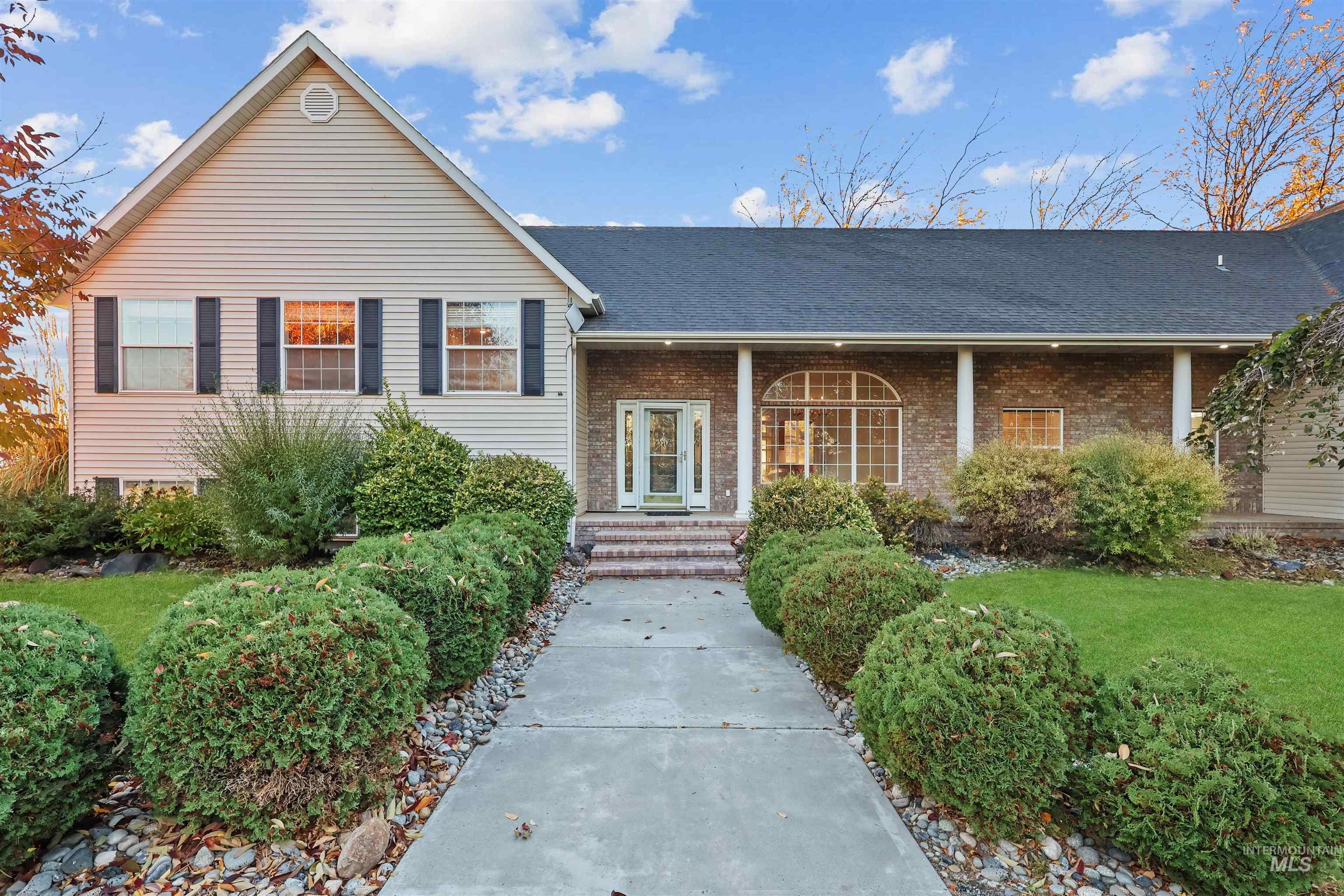 Tri-level home with a porch, a shingled roof, brick siding, and a front yard