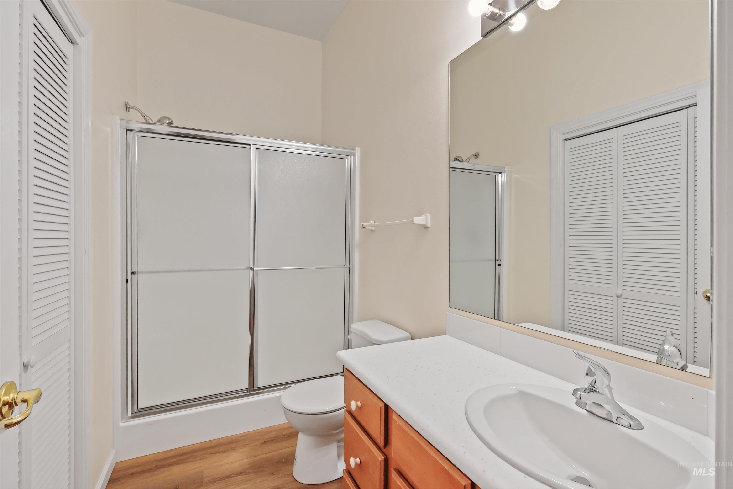 Bathroom featuring a closet, vanity, light wood-style floors, and a shower stall