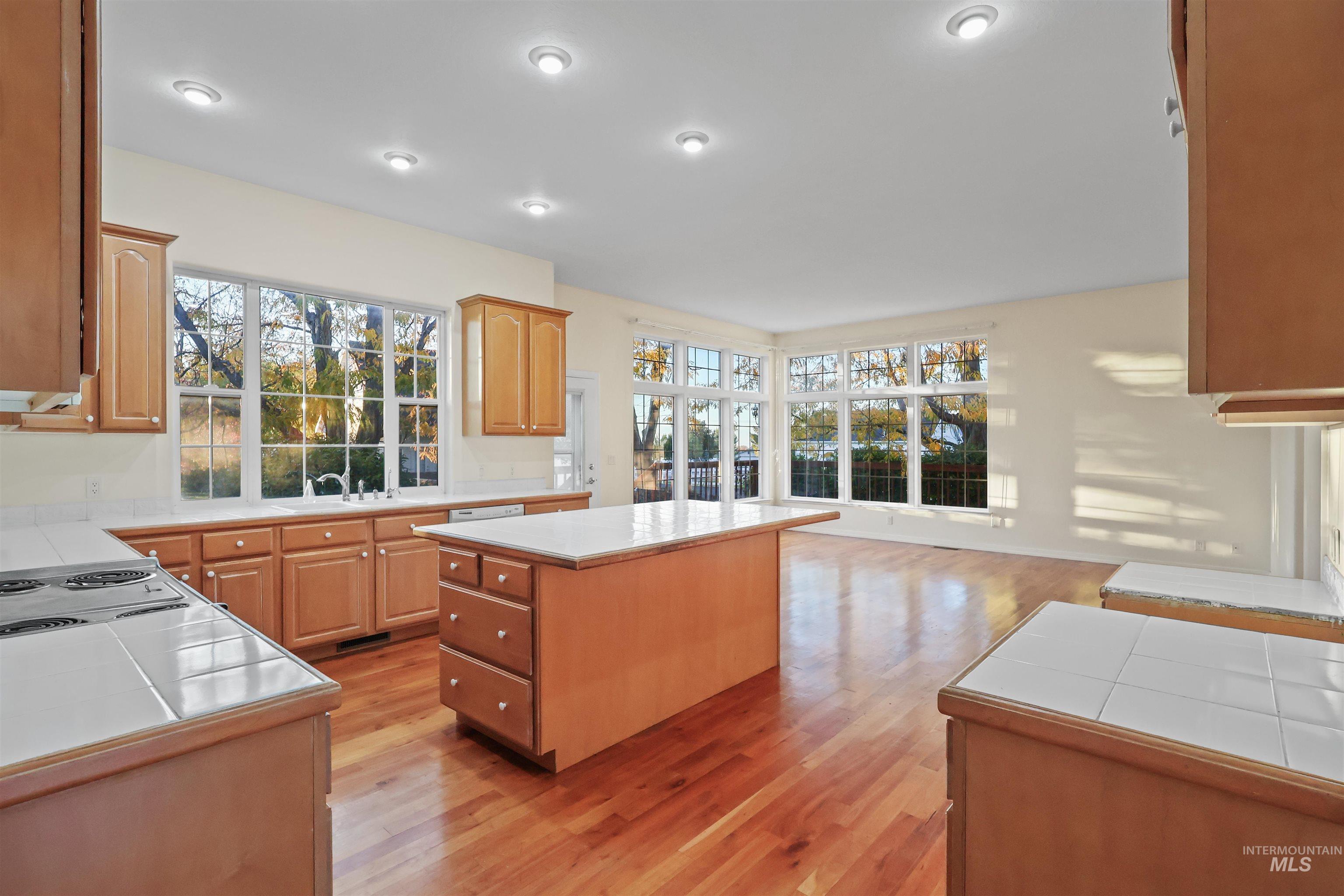 Kitchen featuring a center island, tile counters, light wood-style flooring, and healthy amount of natural light