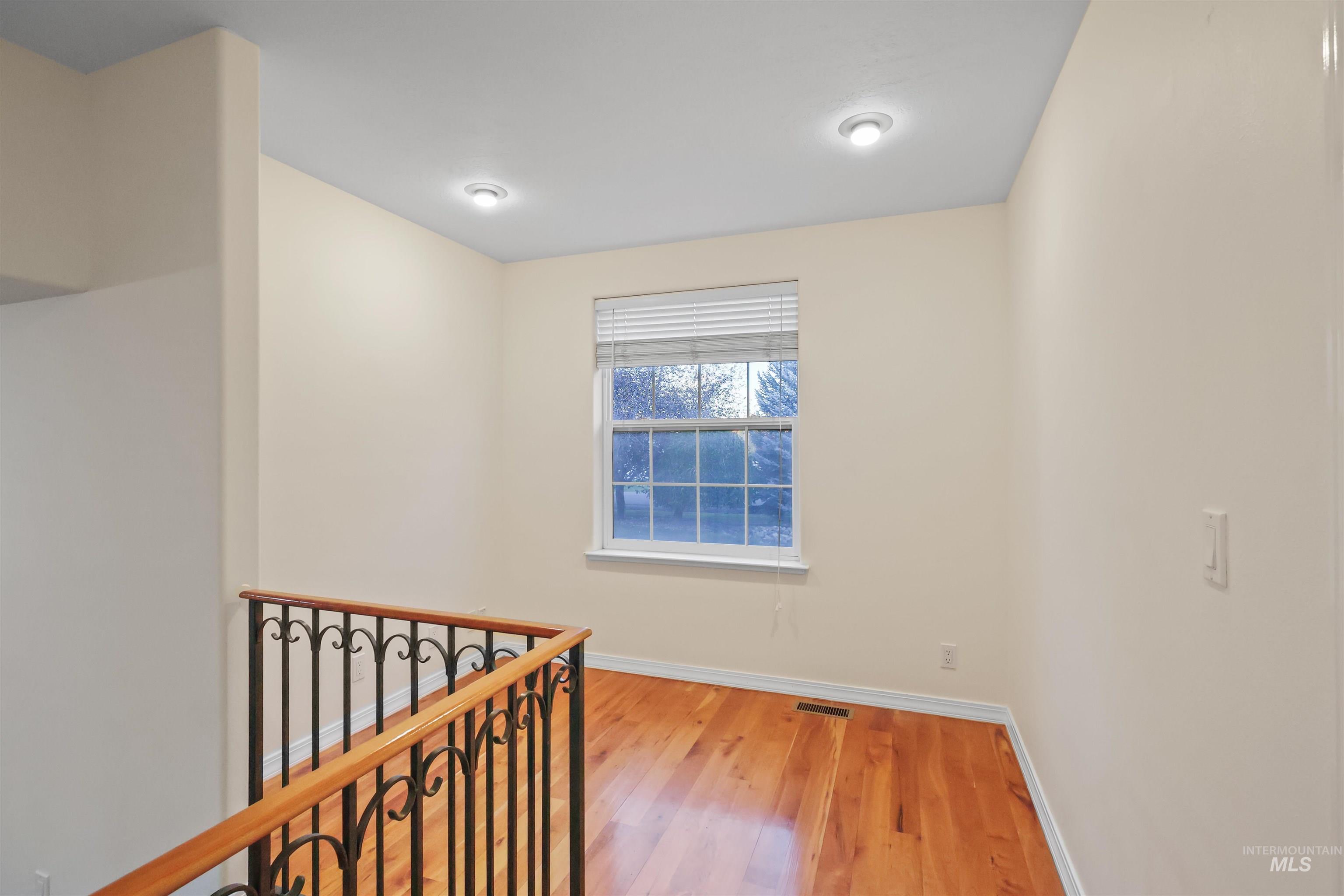 Corridor with light wood-type flooring and an upstairs landing