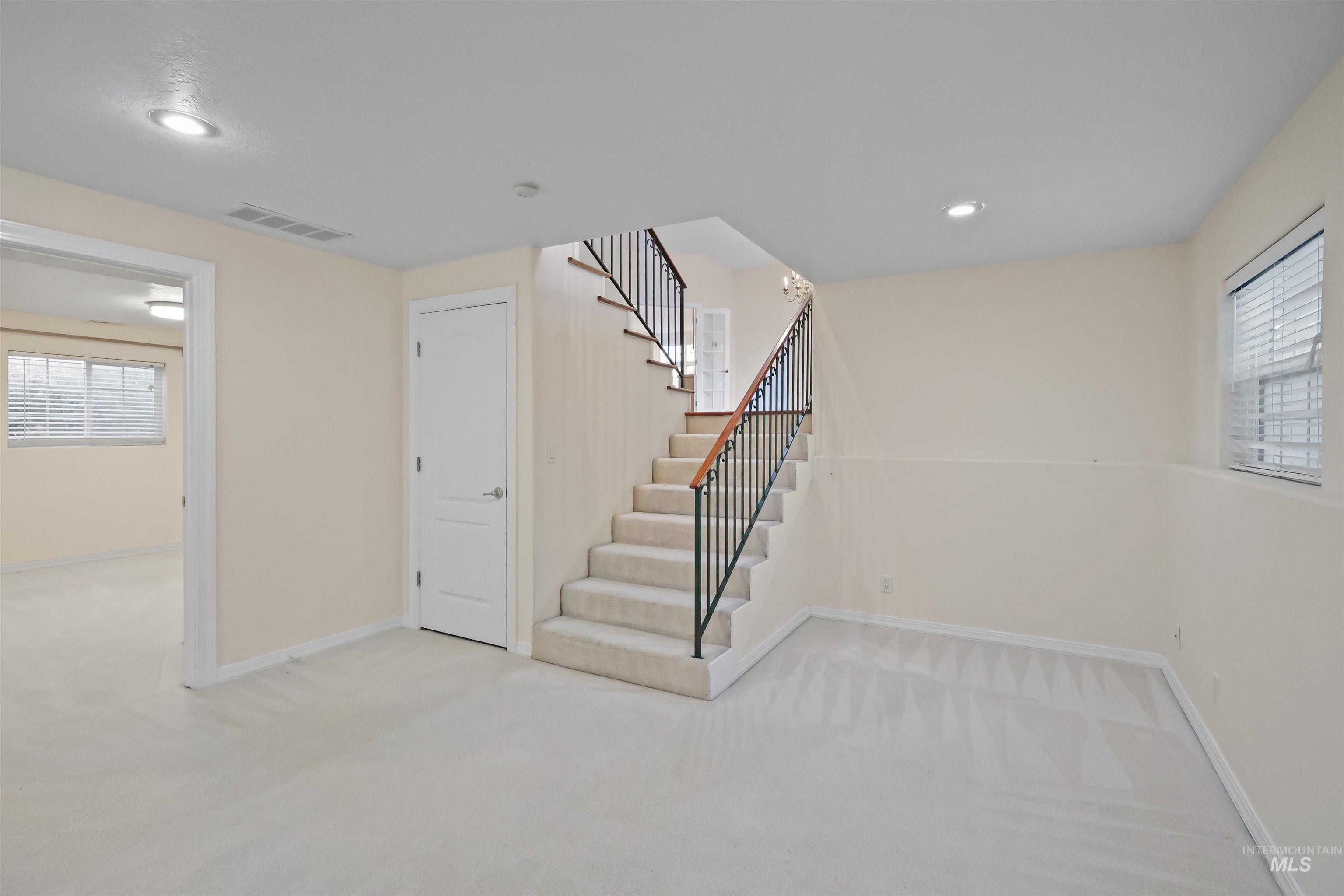 Below grade area with light carpet, stairway, and recessed lighting
