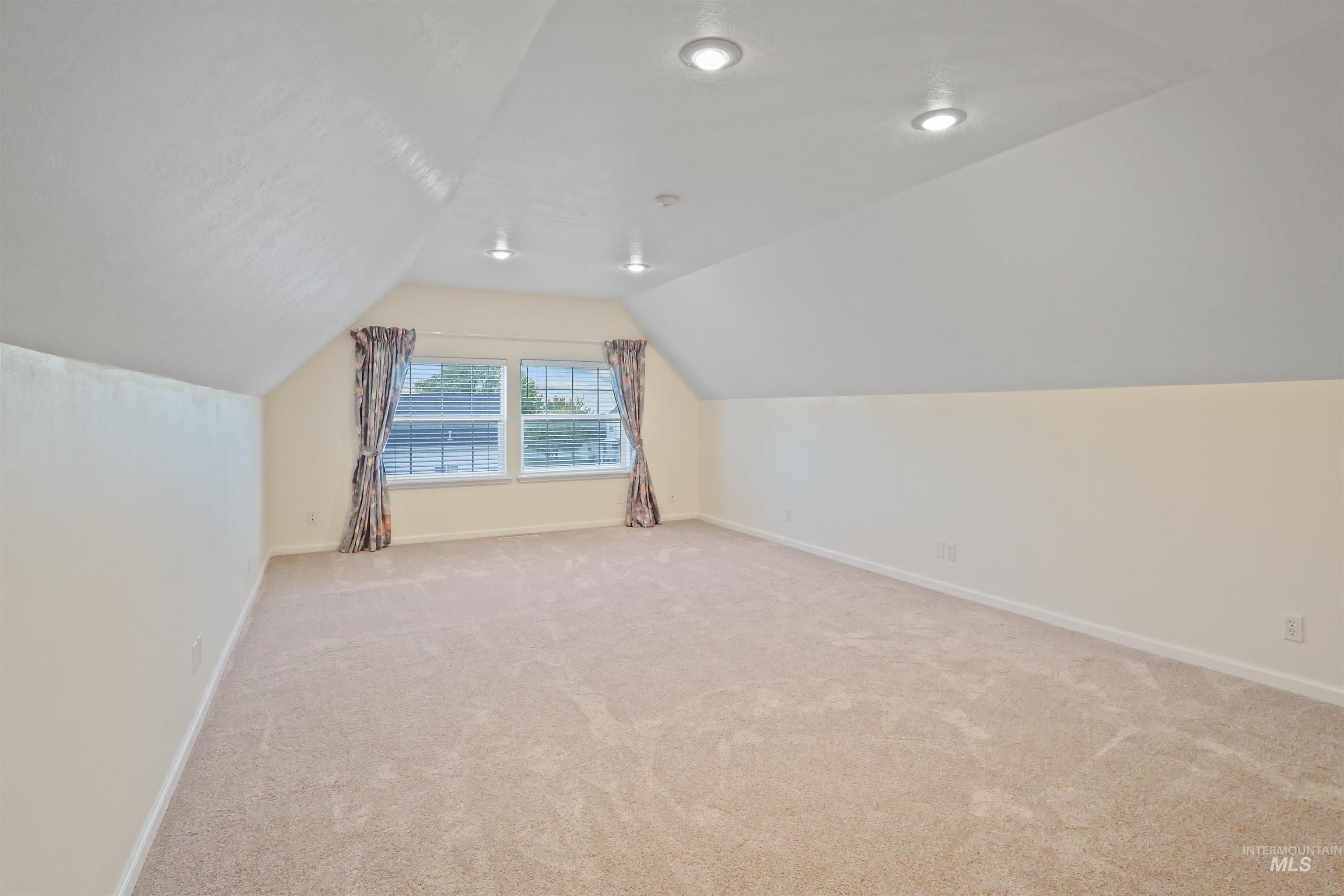 Bonus room featuring vaulted ceiling and light carpet