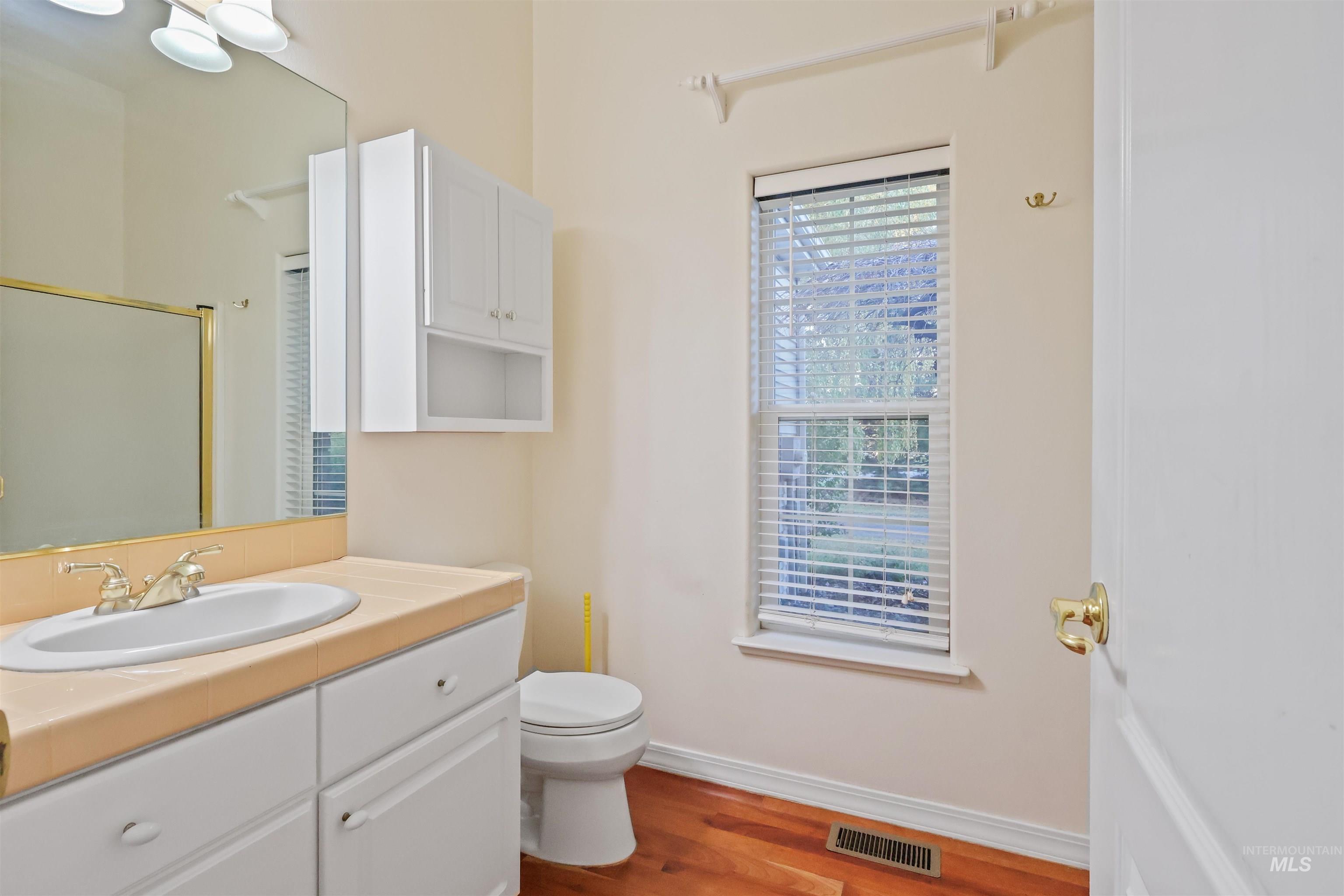 Full bath featuring wood finished floors, vanity, and a shower with shower door