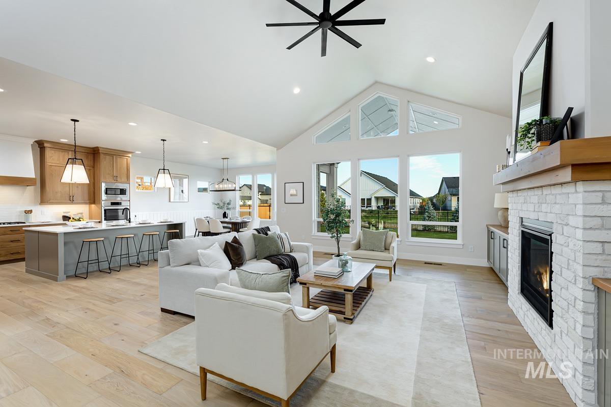 Living room featuring light wood-type flooring, high vaulted ceiling, a fireplace, recessed lighting, and a ceiling fan