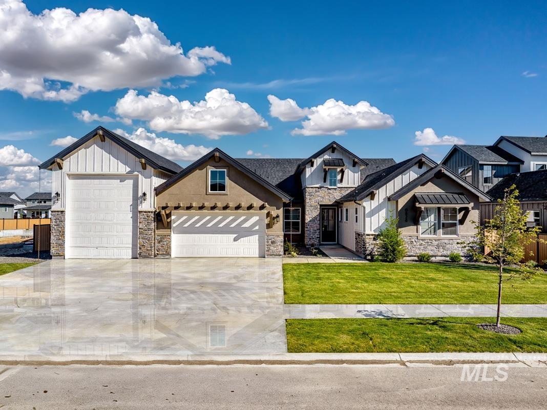 Modern farmhouse featuring stone siding, a front yard, concrete driveway, a garage, and board and batten siding