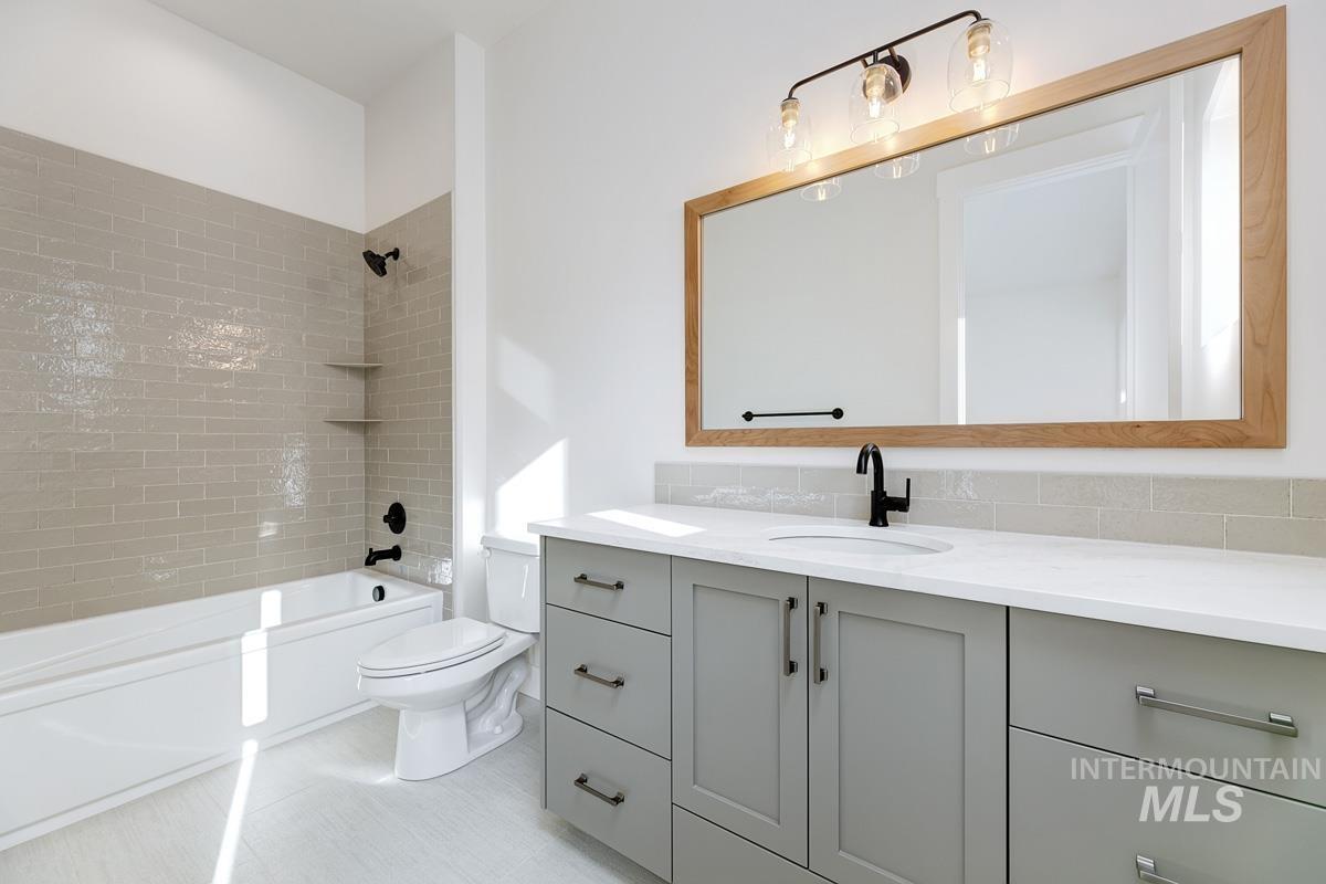 Bathroom featuring vanity,  shower combination, and decorative backsplash