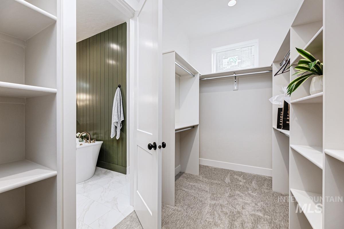 Walk in closet featuring light marble finish flooring