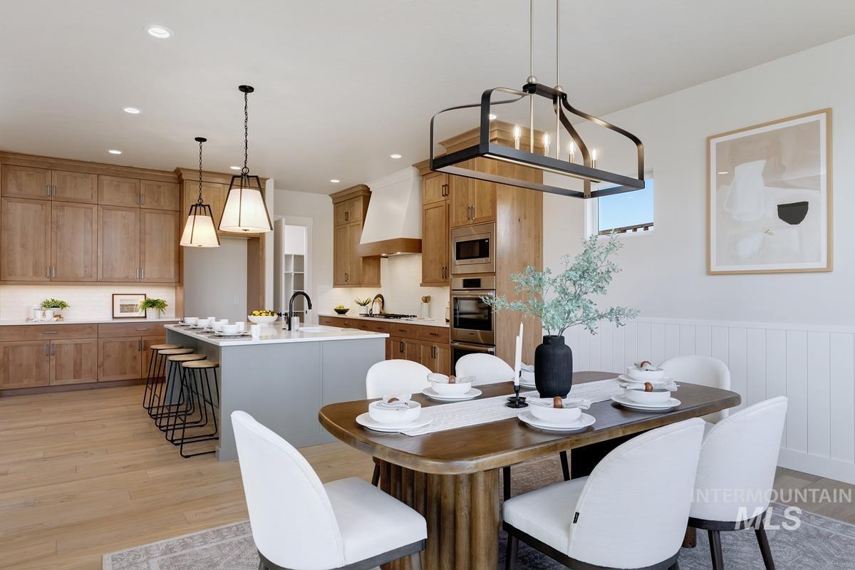 Dining space featuring light wood-style flooring, a wainscoted wall, and recessed lighting