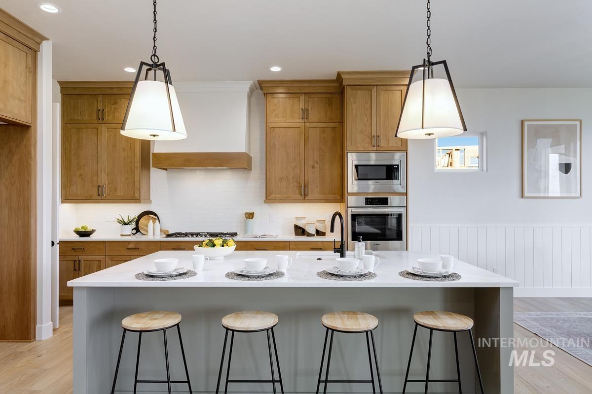 Kitchen with light wood-type flooring, a kitchen breakfast bar, brown cabinets, stainless steel appliances, and recessed lighting