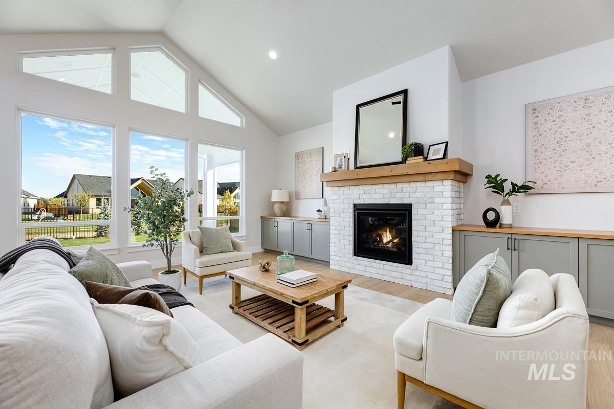 Living room with wood finished floors, high vaulted ceiling, a fireplace, and recessed lighting