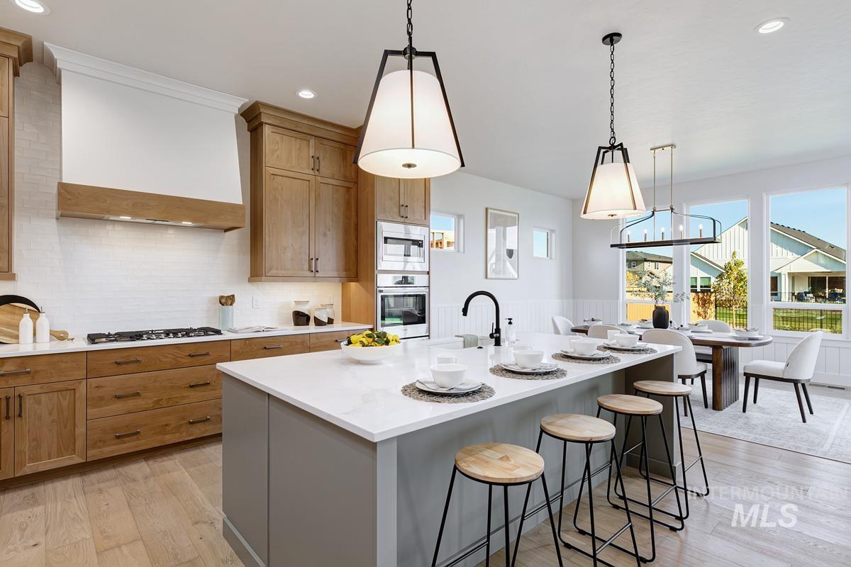 Kitchen featuring a kitchen bar, light wood-style flooring, a kitchen island with sink, pendant lighting, and recessed lighting