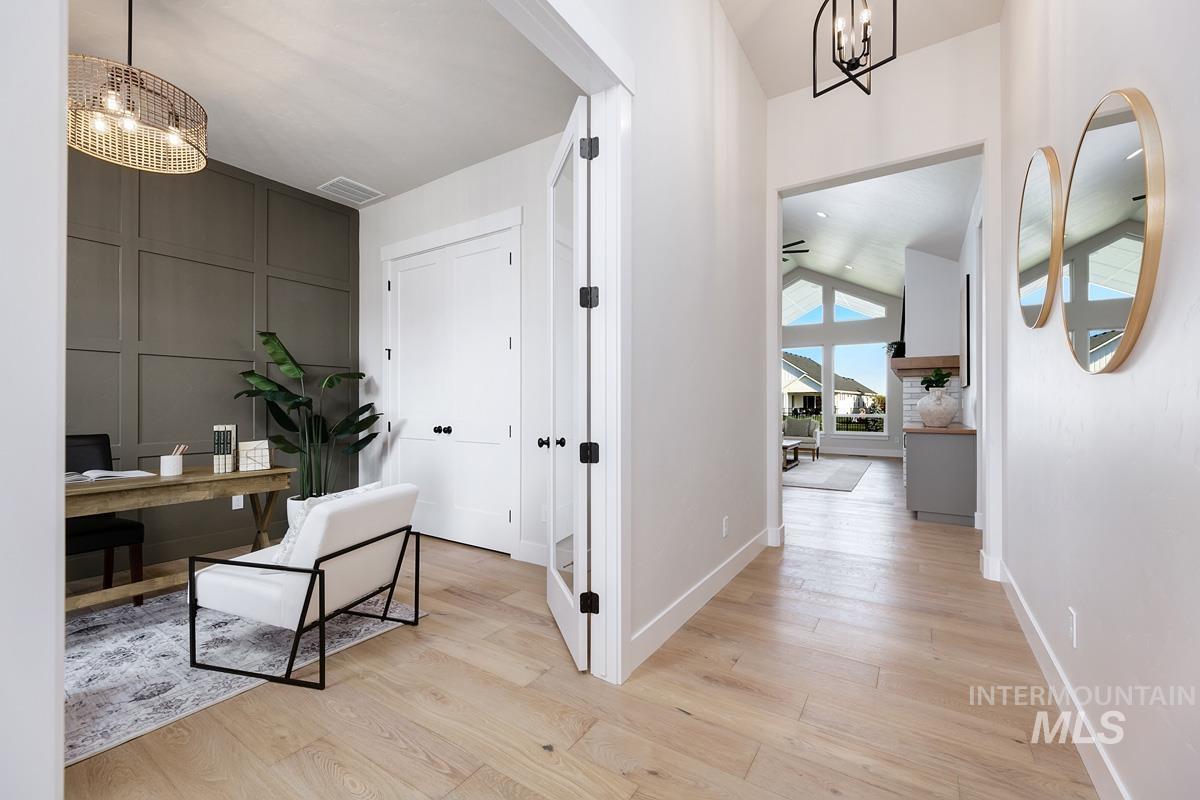 Home office featuring a chandelier, light wood-style floors, and lofted ceiling