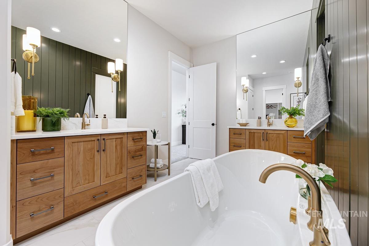 Full bathroom featuring a freestanding bath, two vanities, recessed lighting, and wooden walls