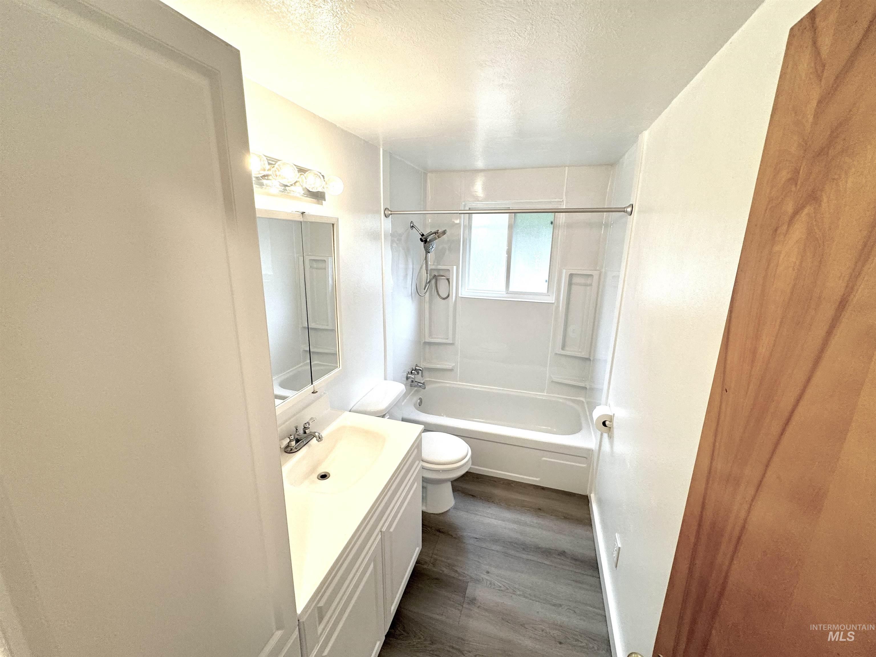 Full bath with shower / bath combination, vanity, a textured ceiling, and dark wood finished floors