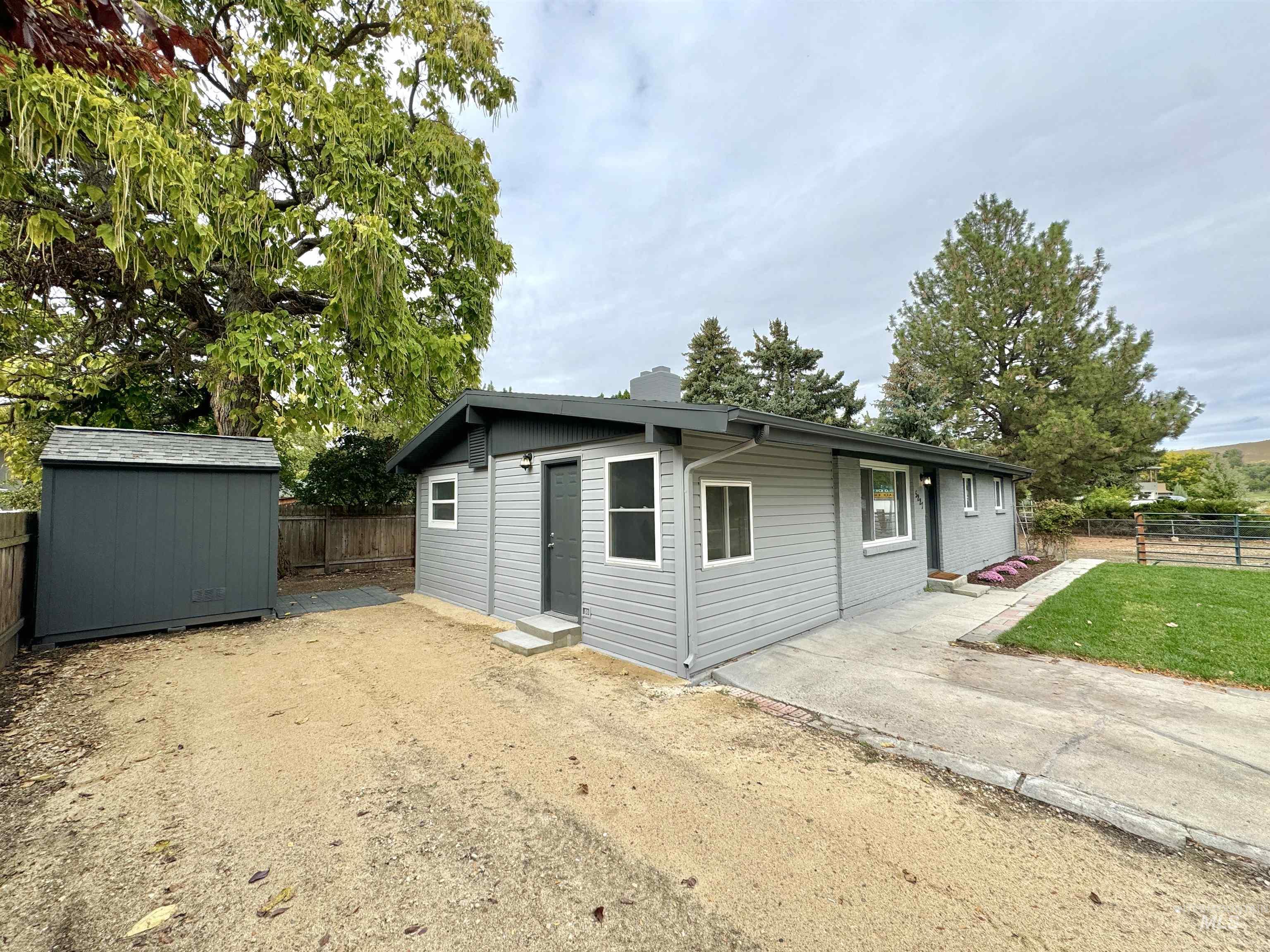 View of side of home featuring a fenced backyard, a chimney, and a storage shed