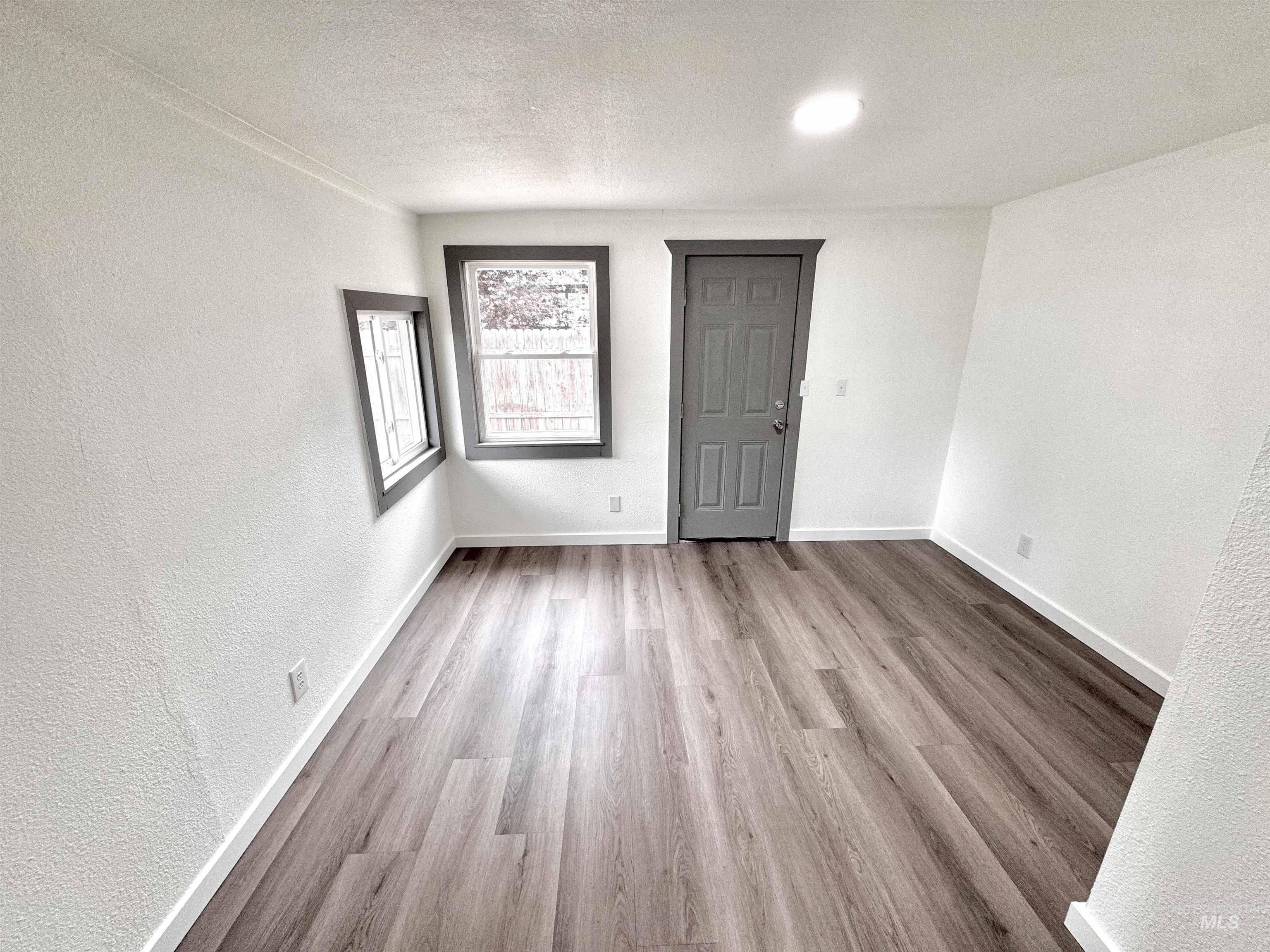 Unfurnished room featuring a textured wall, light wood-style flooring, and a textured ceiling