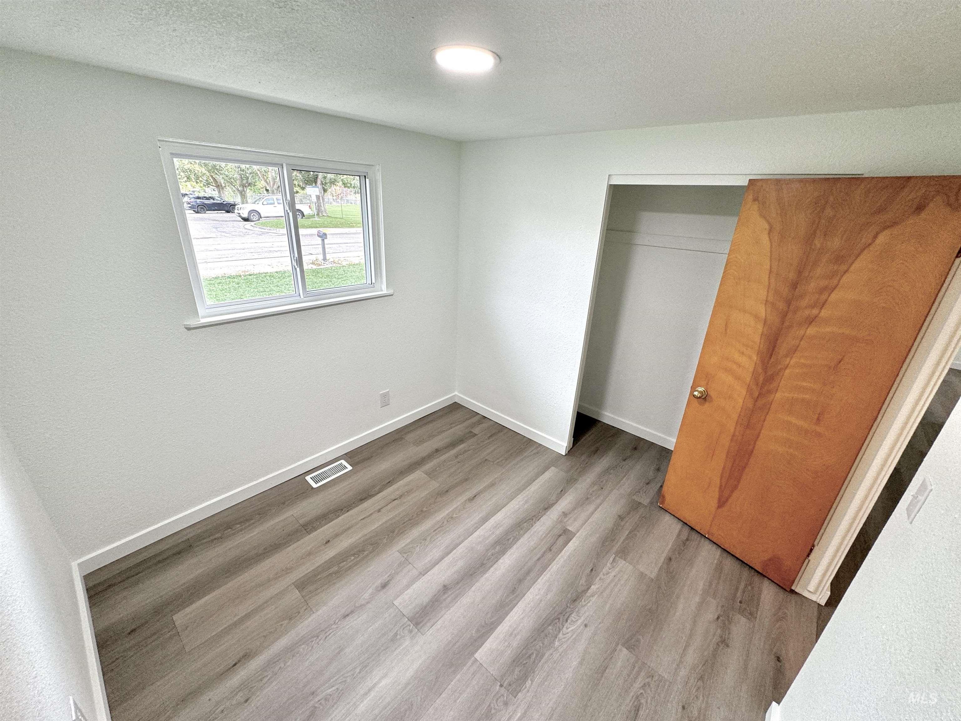Unfurnished bedroom with a textured ceiling, light wood-style flooring, and a closet