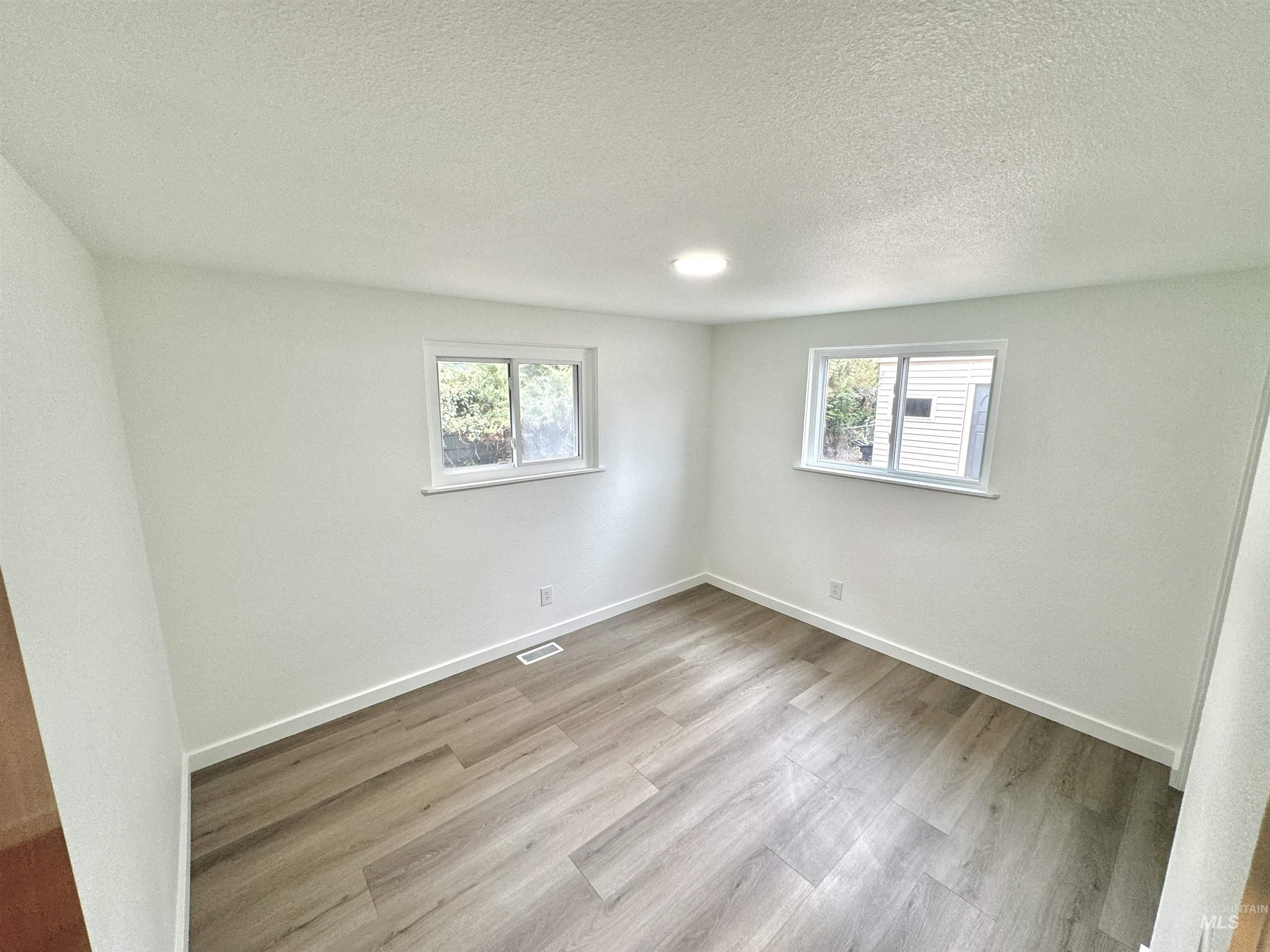 Empty room with light wood-style floors and a textured ceiling