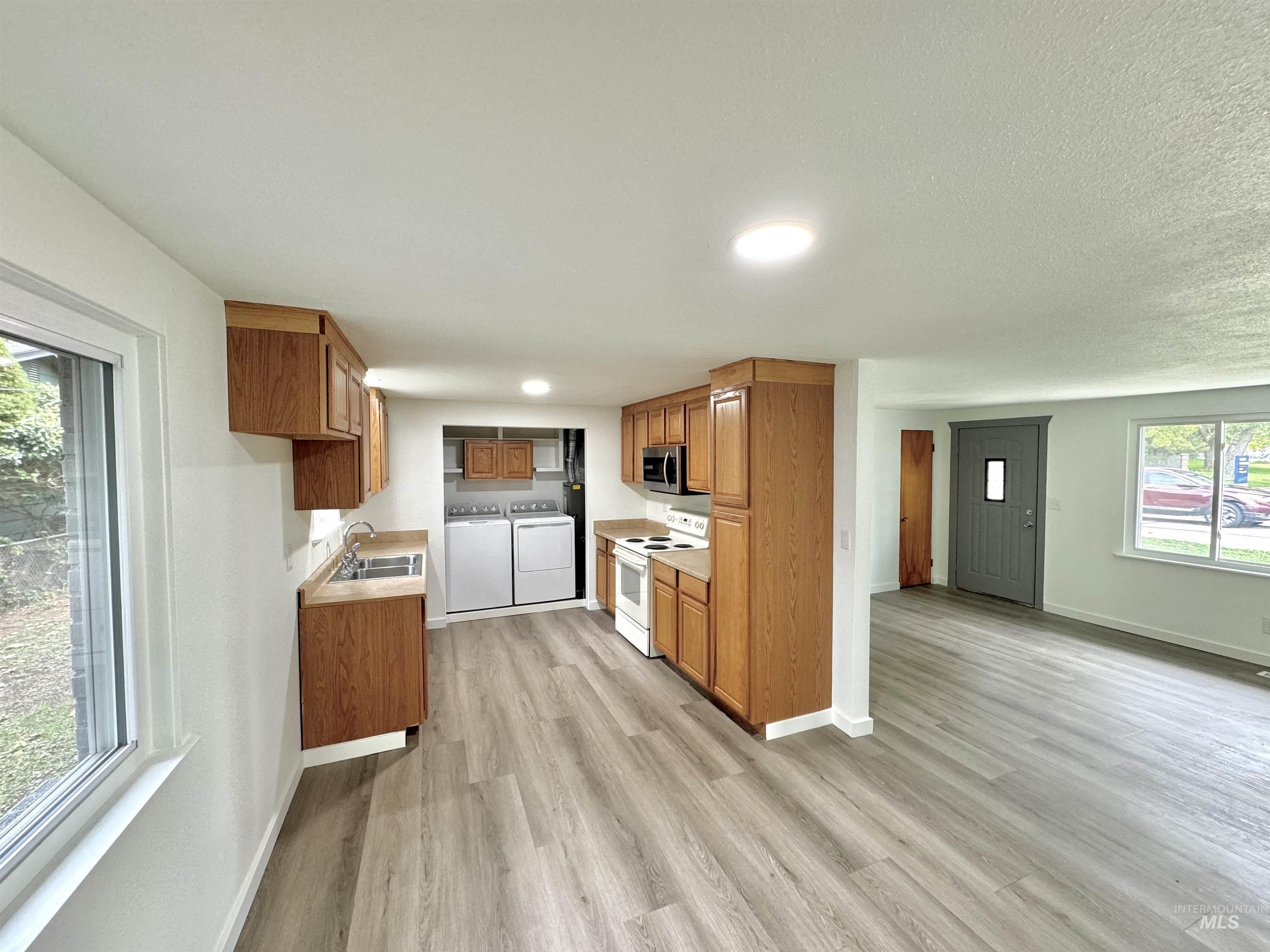 Kitchen featuring brown cabinetry, light countertops, washing machine and dryer, white electric stove, and recessed lighting