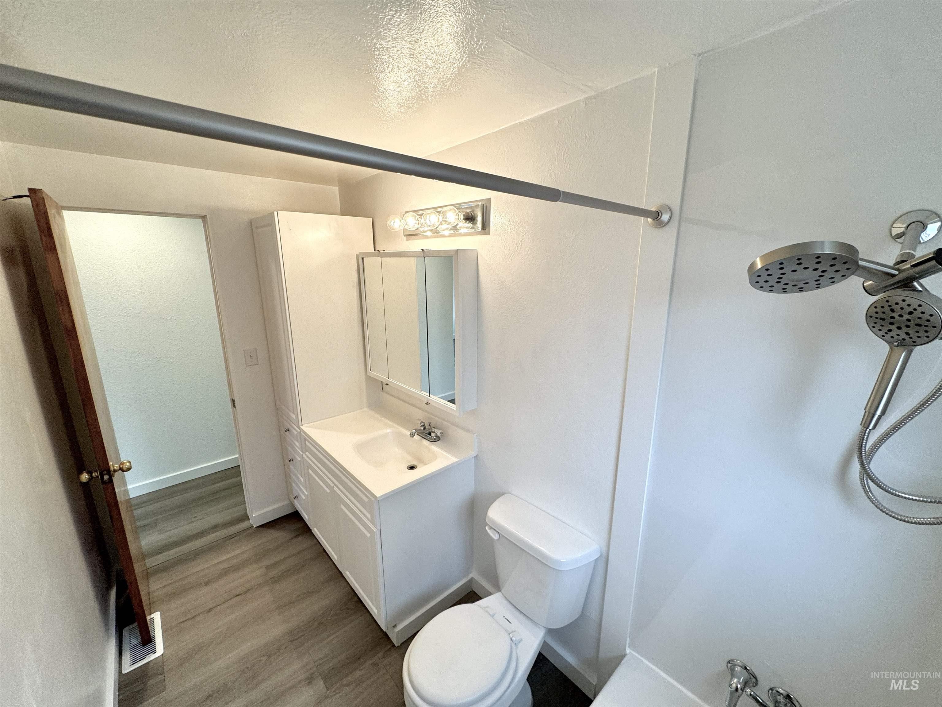 Bathroom featuring vanity, wood finished floors, a textured ceiling, and a shower