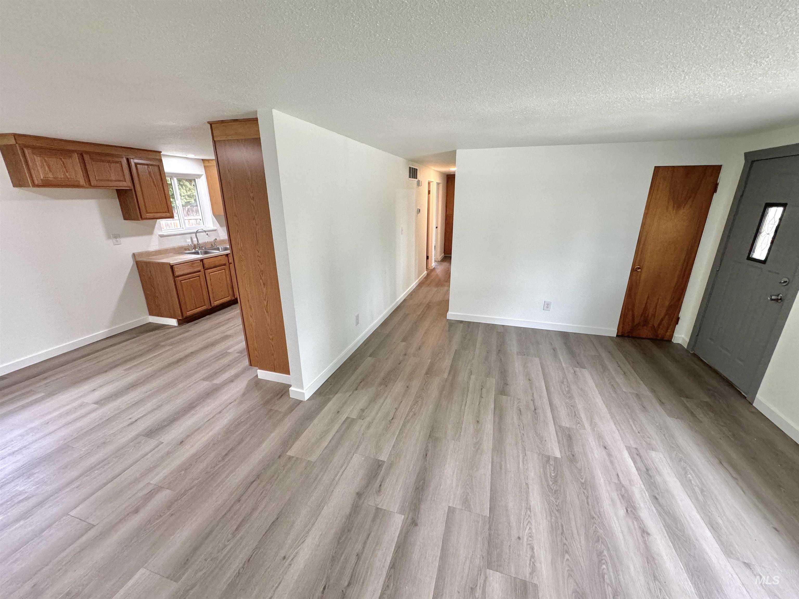 Unfurnished living room featuring a textured ceiling and light wood-style flooring