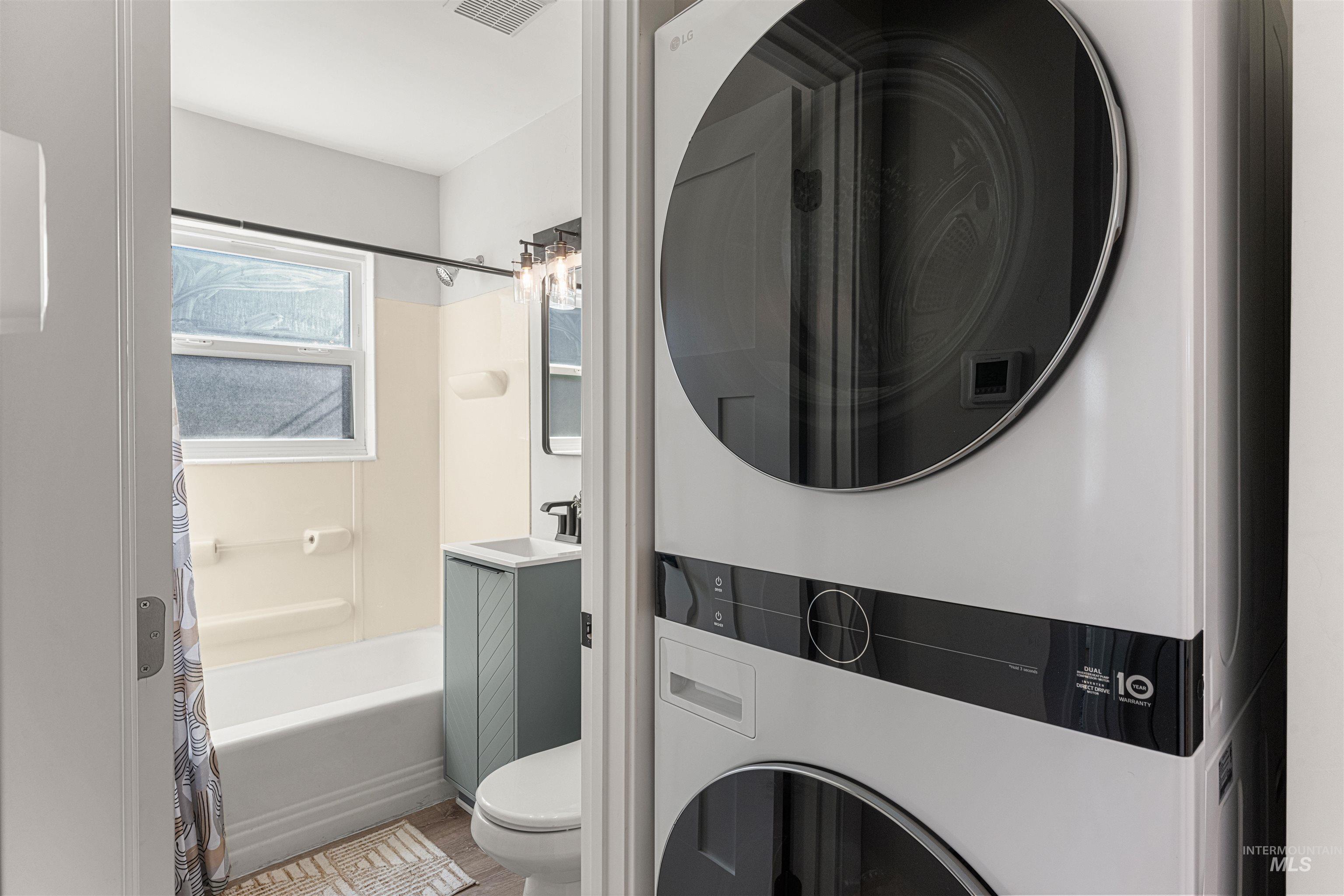 Bedroom with a closet, wood finished floors, and washer / dryer
