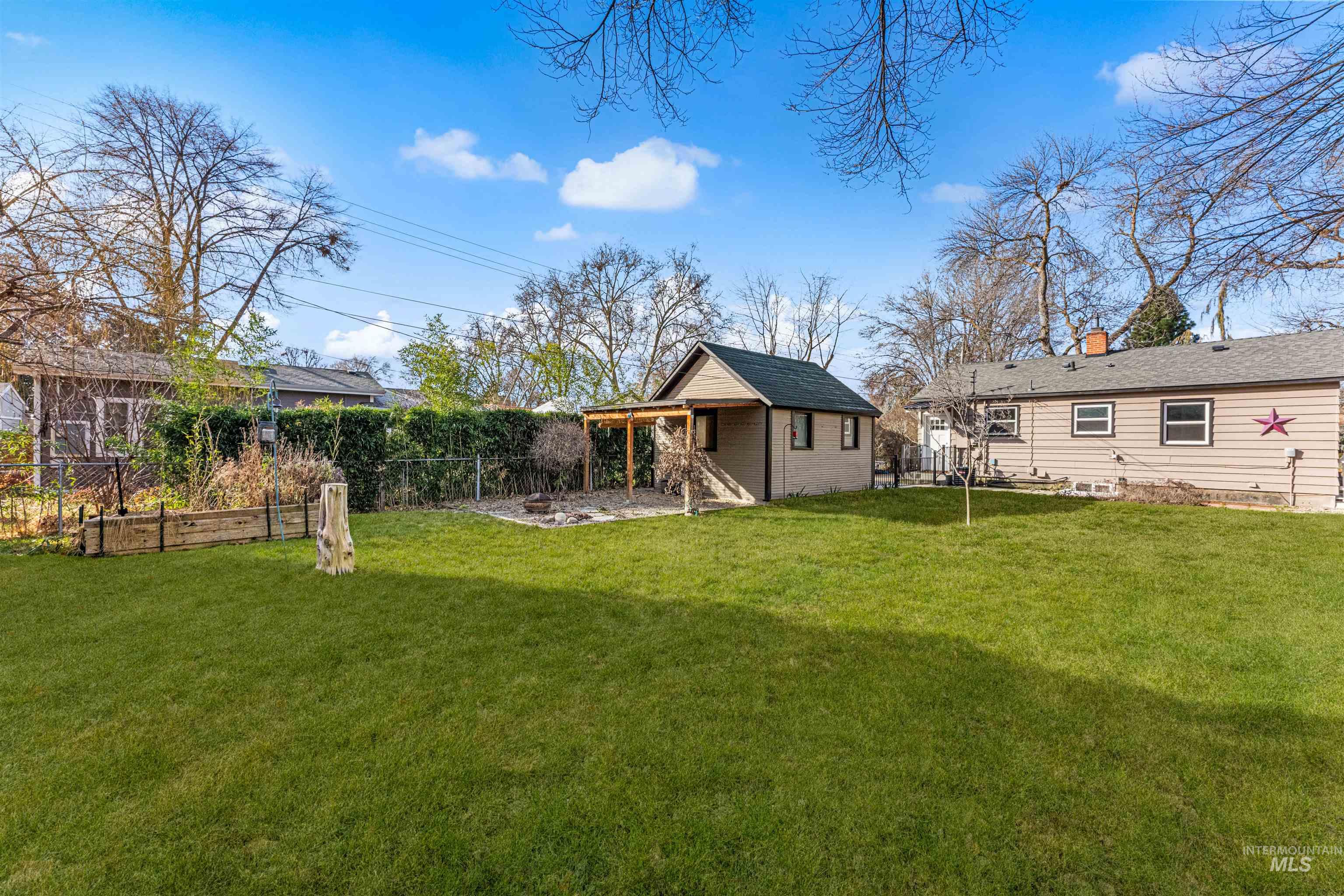 Back of property with a patio, a fenced backyard, an outbuilding, a chimney, and a vegetable garden