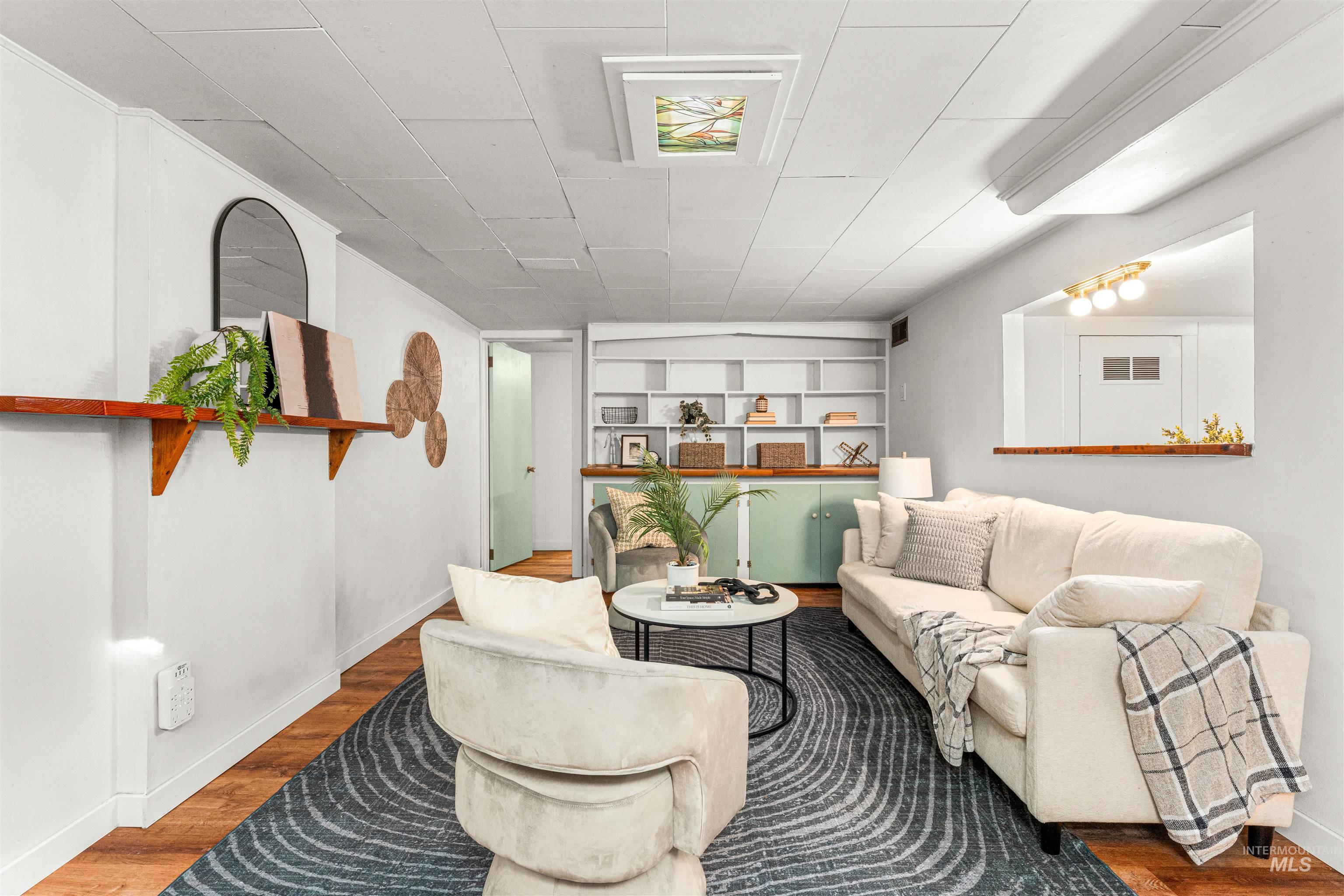 Laundry area with stacked washer / drying machine, wood finished floors, and recessed lighting