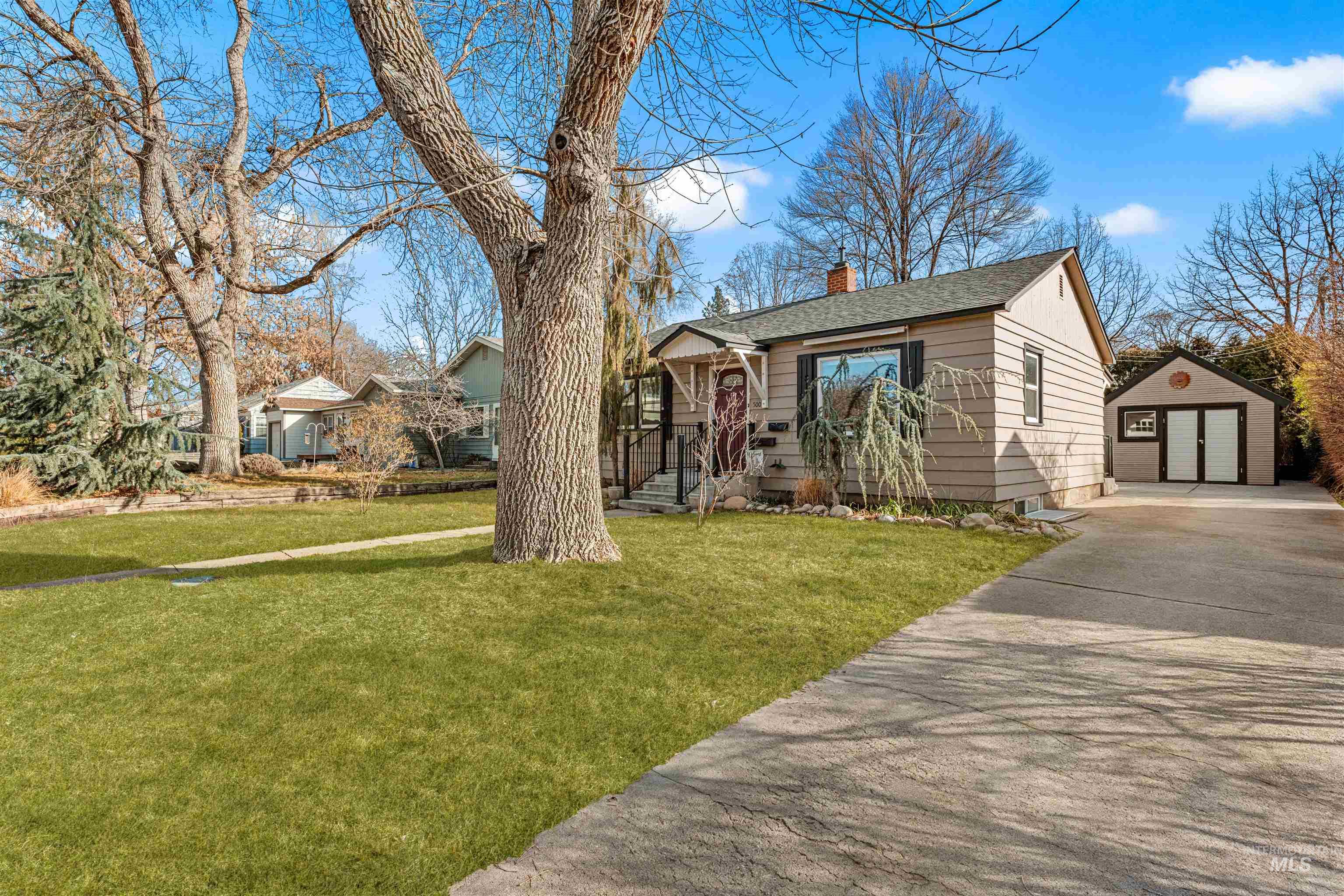 View of front of home with an outbuilding, a garage, a chimney, a front yard, and a shingled roof