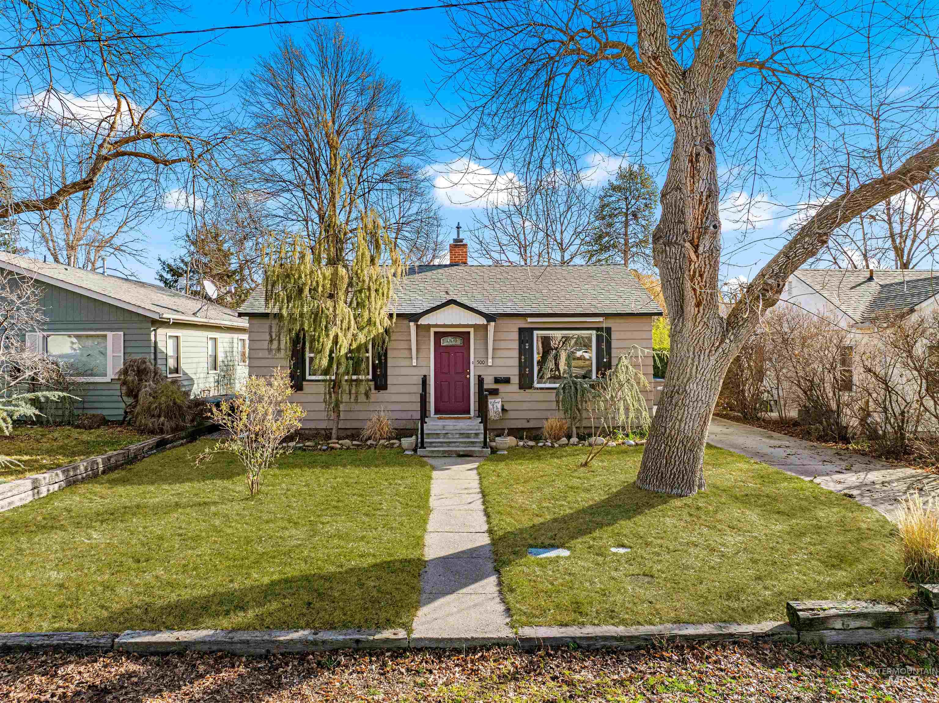 Bungalow-style house with a chimney, a shingled roof, and a front lawn