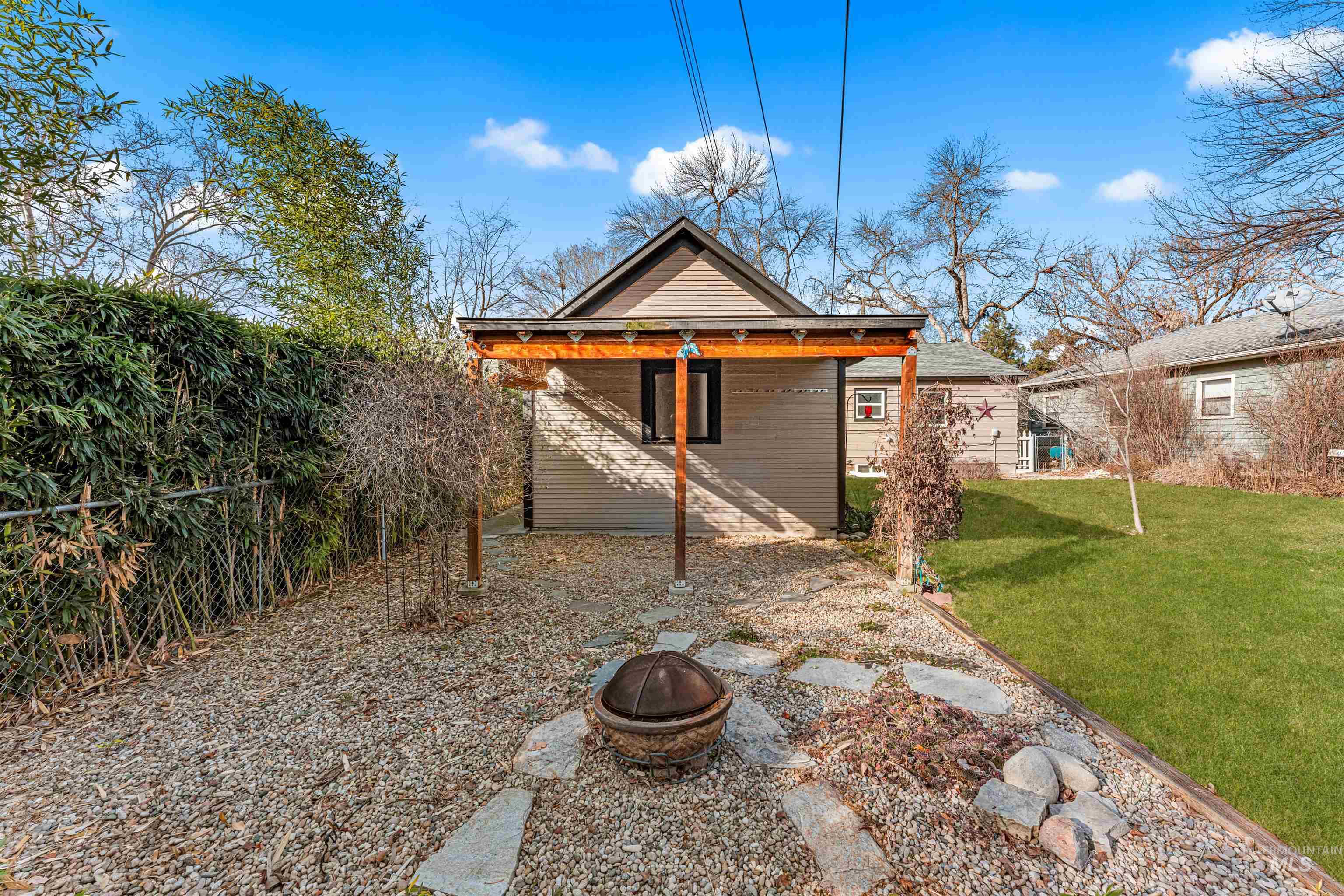 Rear view of property with a lawn, a fire pit, and a patio