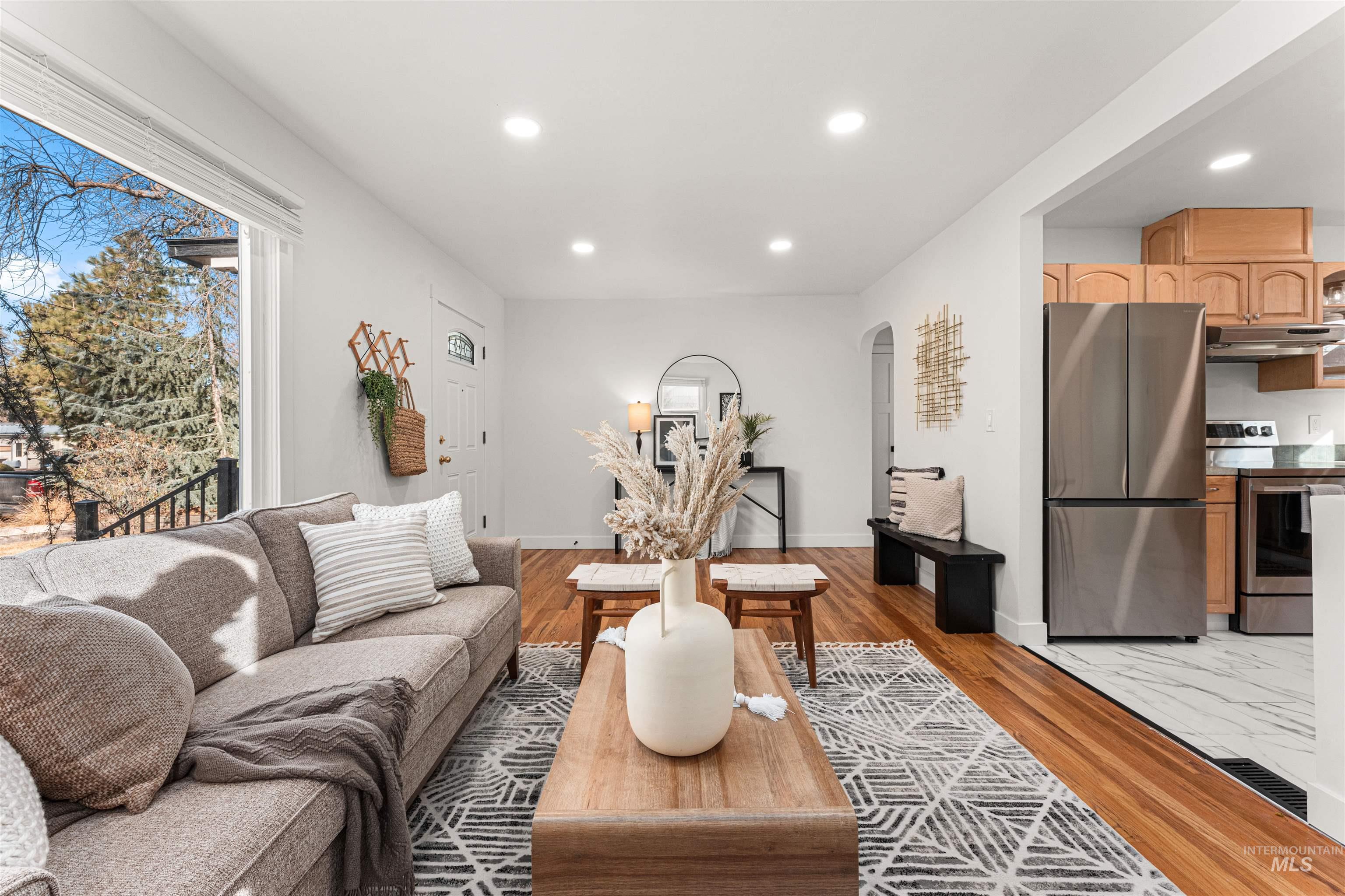 Living room featuring light wood-style flooring, recessed lighting, and arched walkways