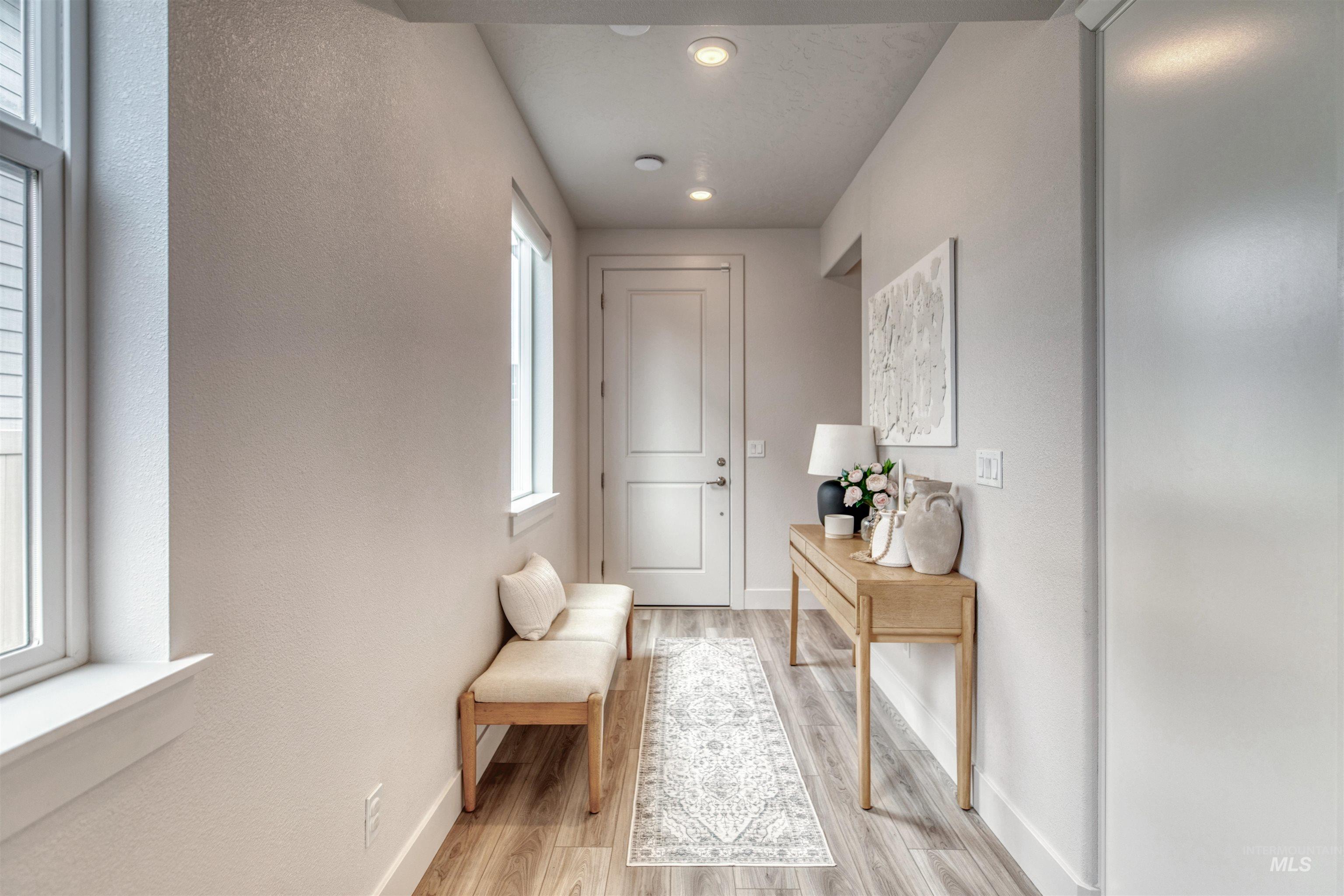 Doorway to outside featuring a textured wall, wood finished floors, and recessed lighting