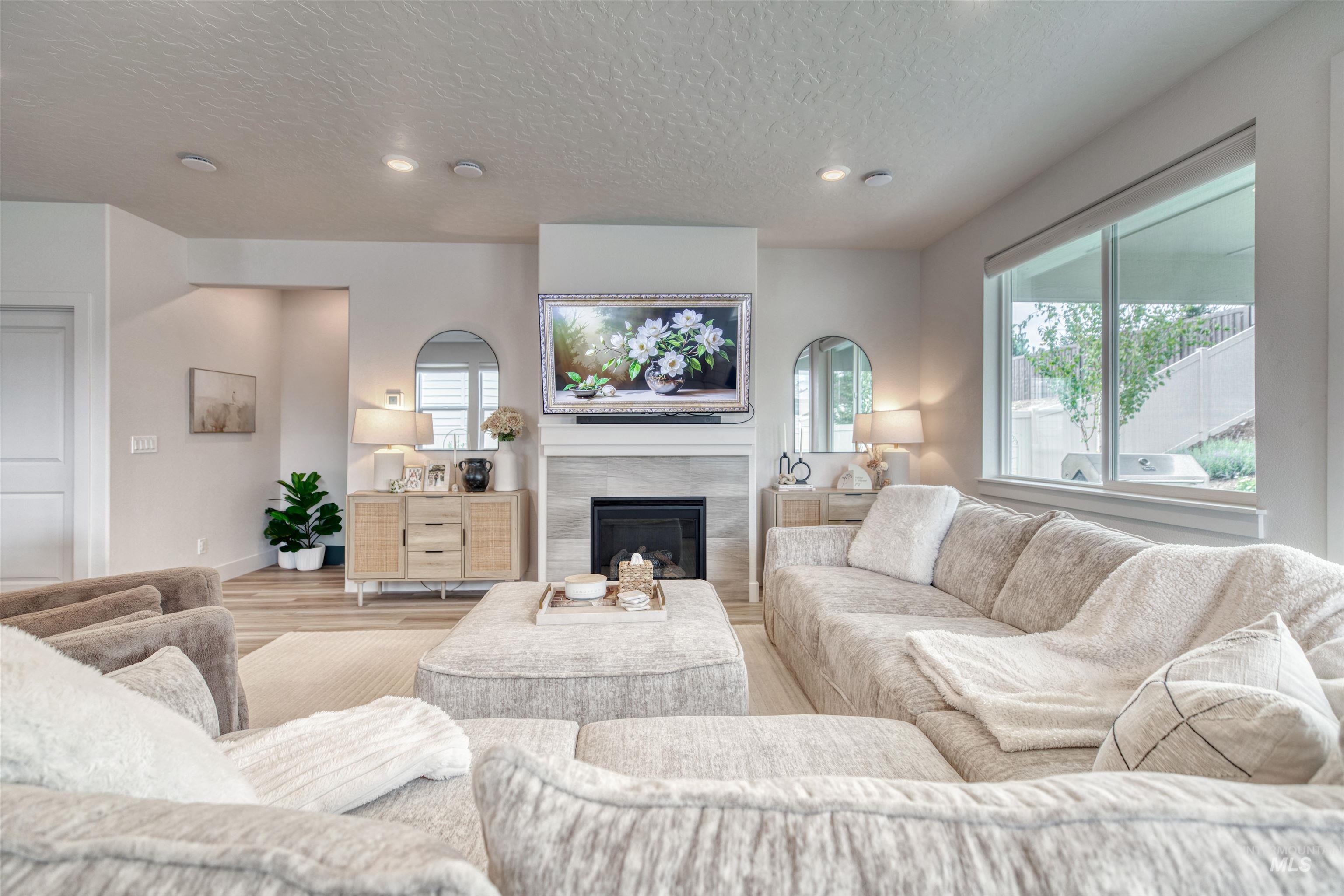 Living room featuring recessed lighting, a fireplace, a textured ceiling, and wood finished floors