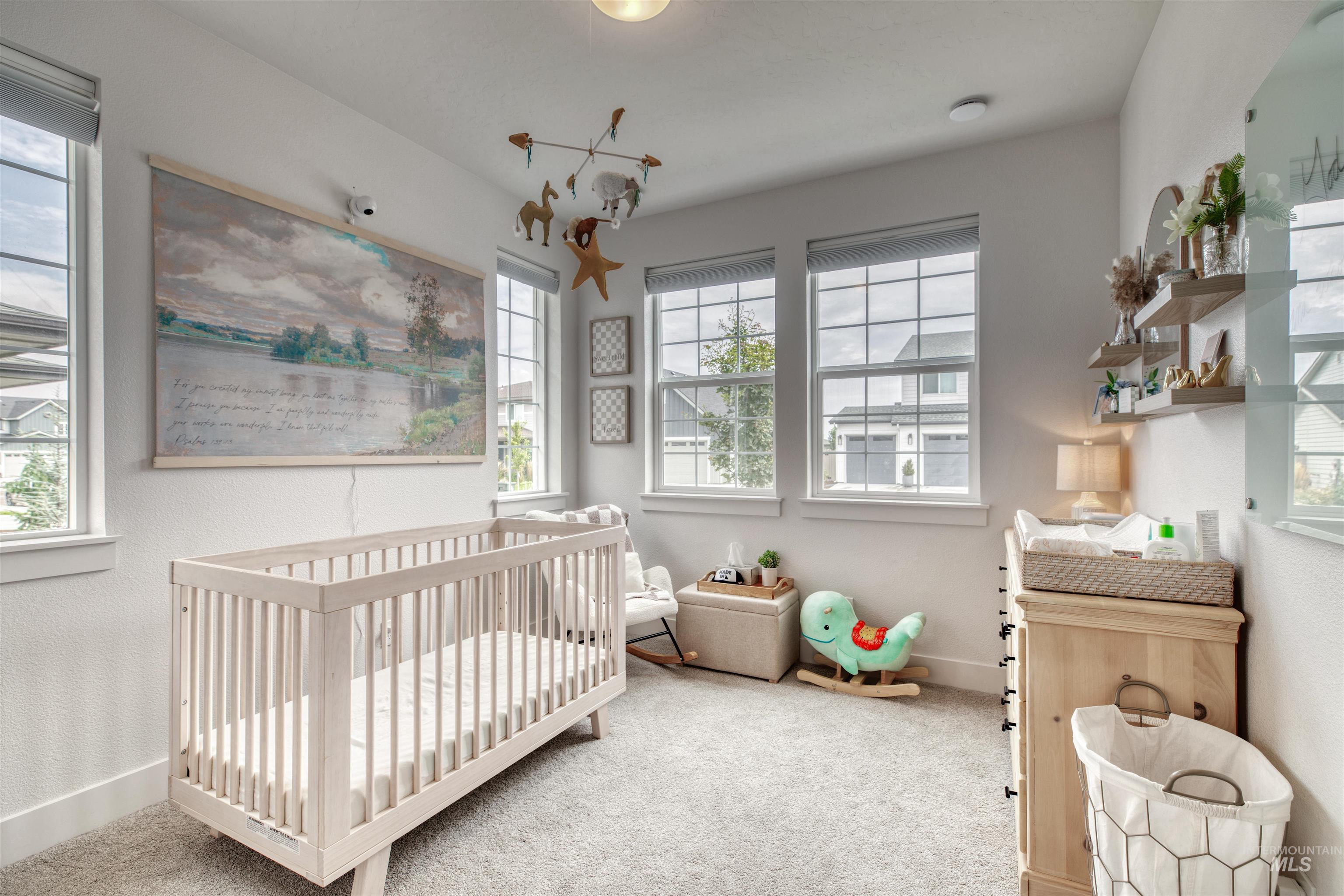 Bedroom with a nursery area, carpet, and a textured wall