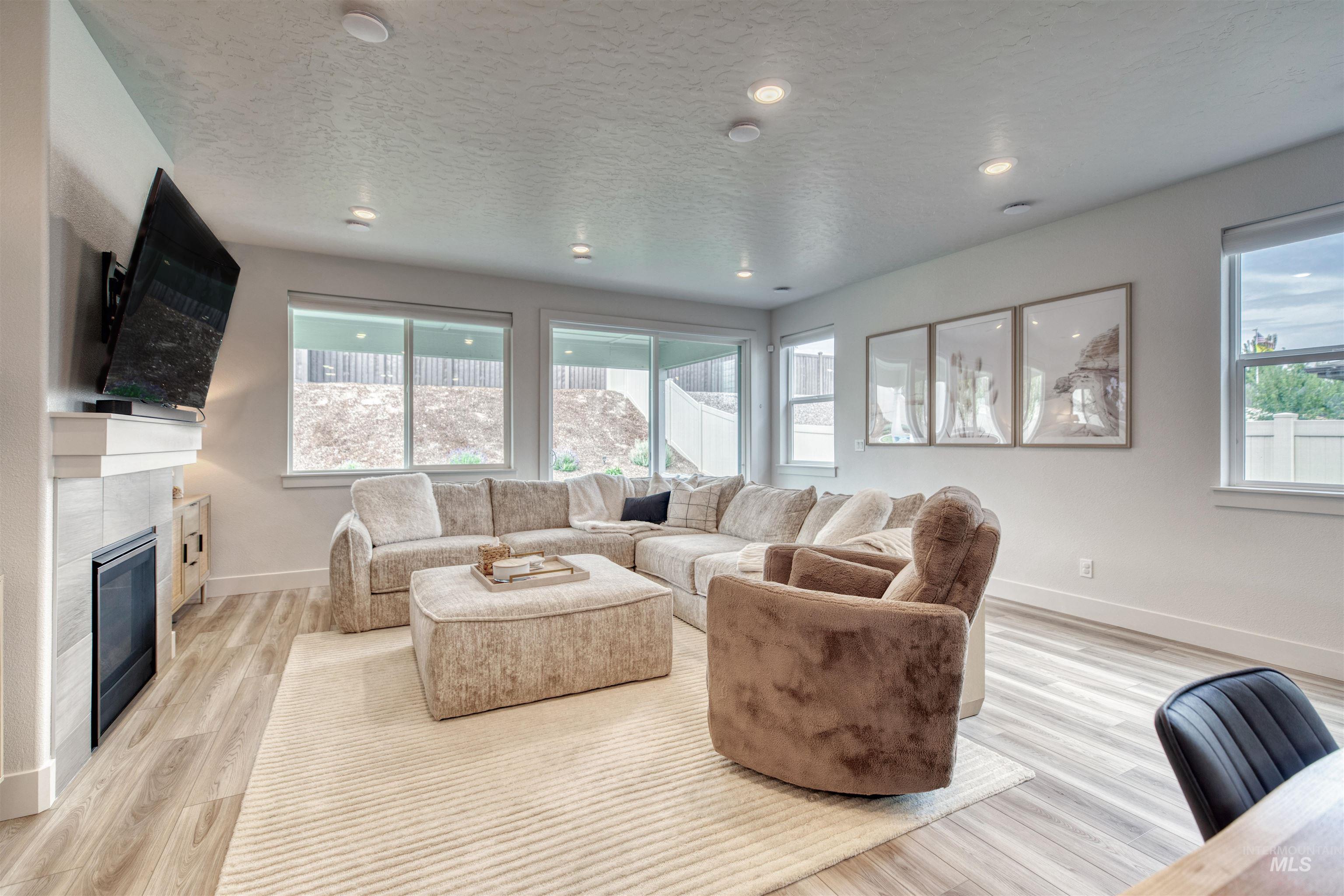 Living area featuring light wood-style floors, a textured ceiling, a tile fireplace, and recessed lighting