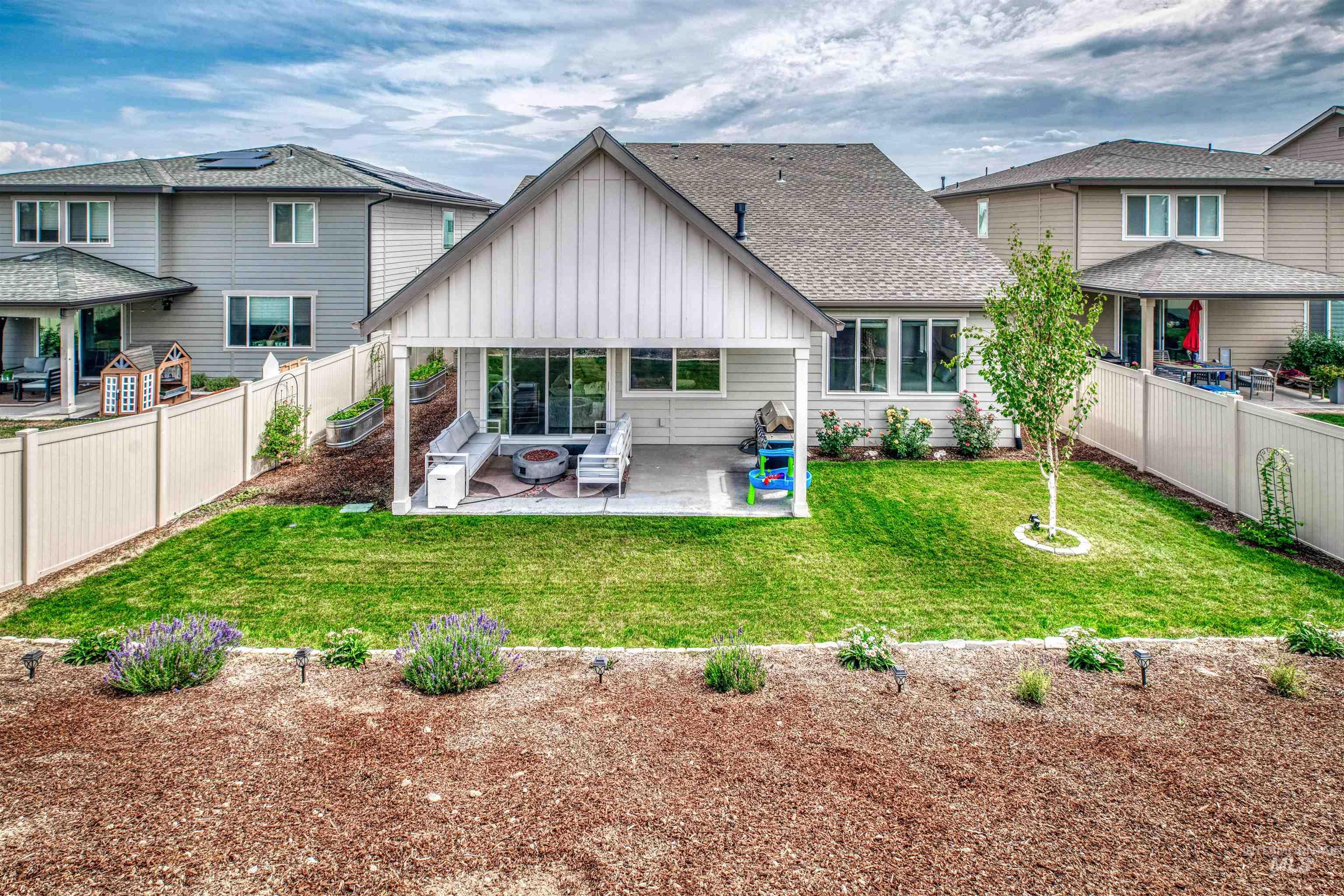 Back of property with board and batten siding, a patio, a fenced backyard, and a shingled roof