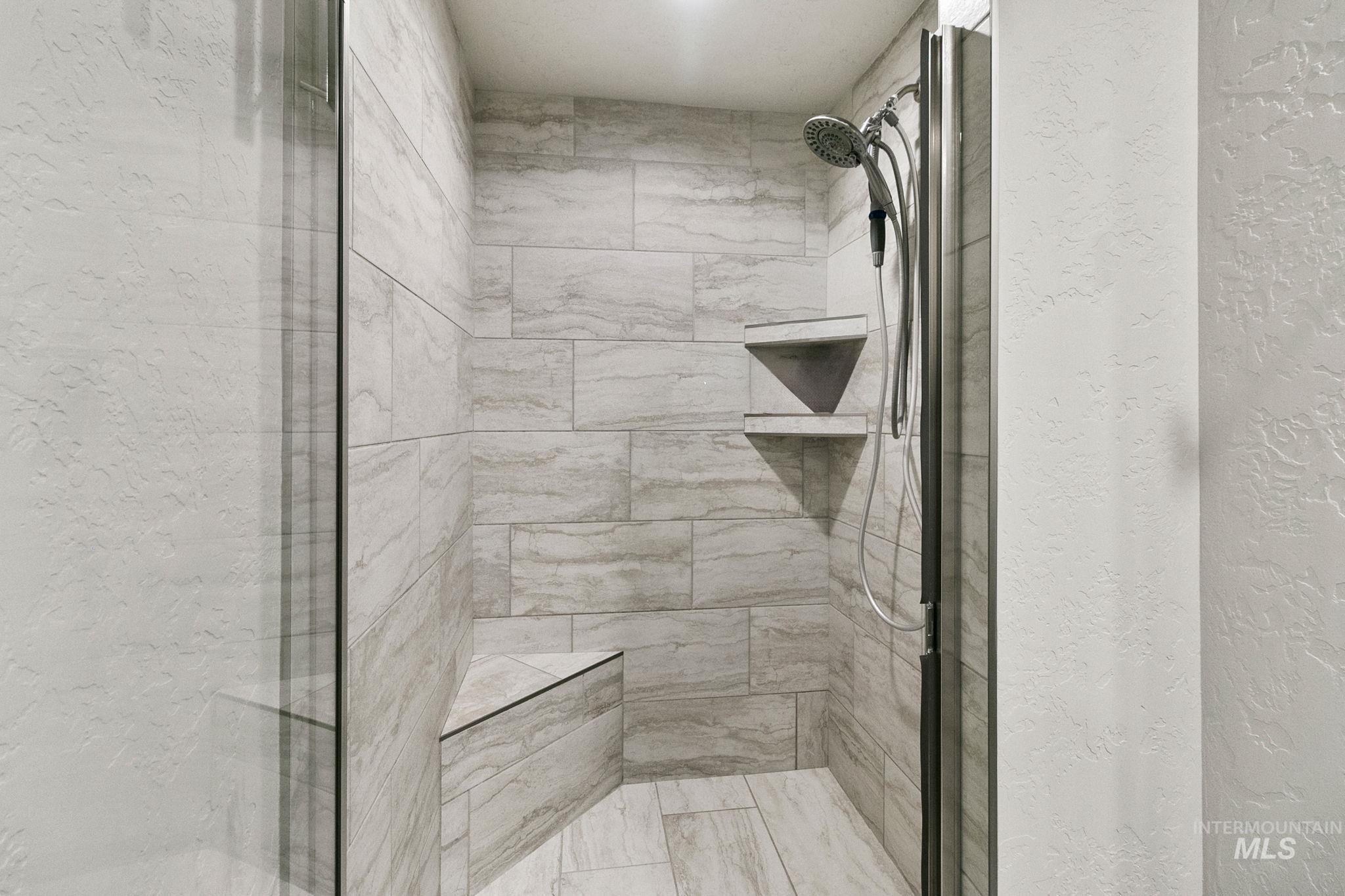 Full bath featuring a shower stall and a textured wall