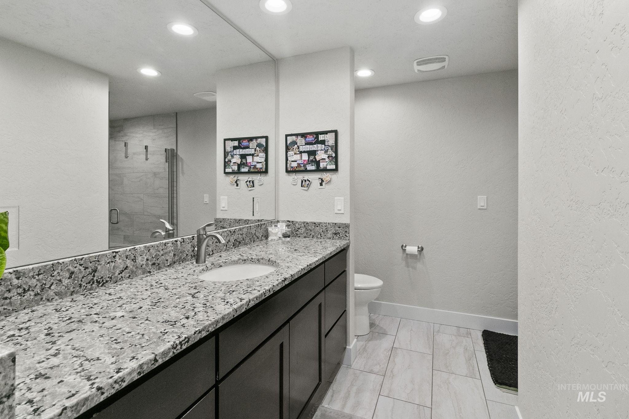 Full bathroom featuring a textured wall, a stall shower, vanity, and recessed lighting