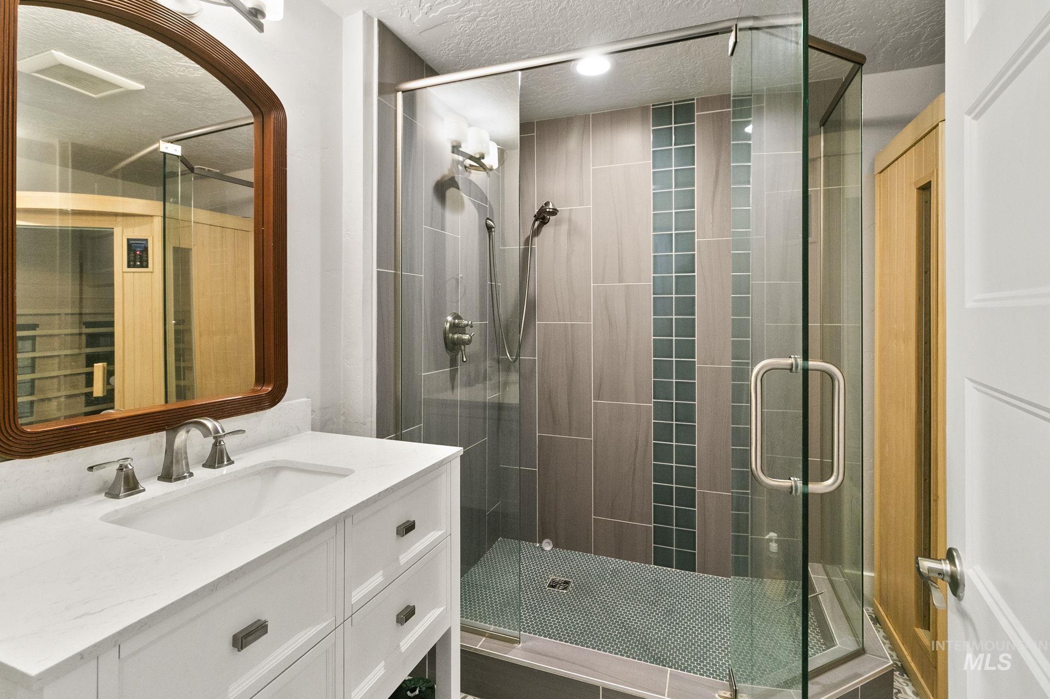Full bathroom featuring vanity, a shower stall, a textured ceiling, and a relaxing sauna