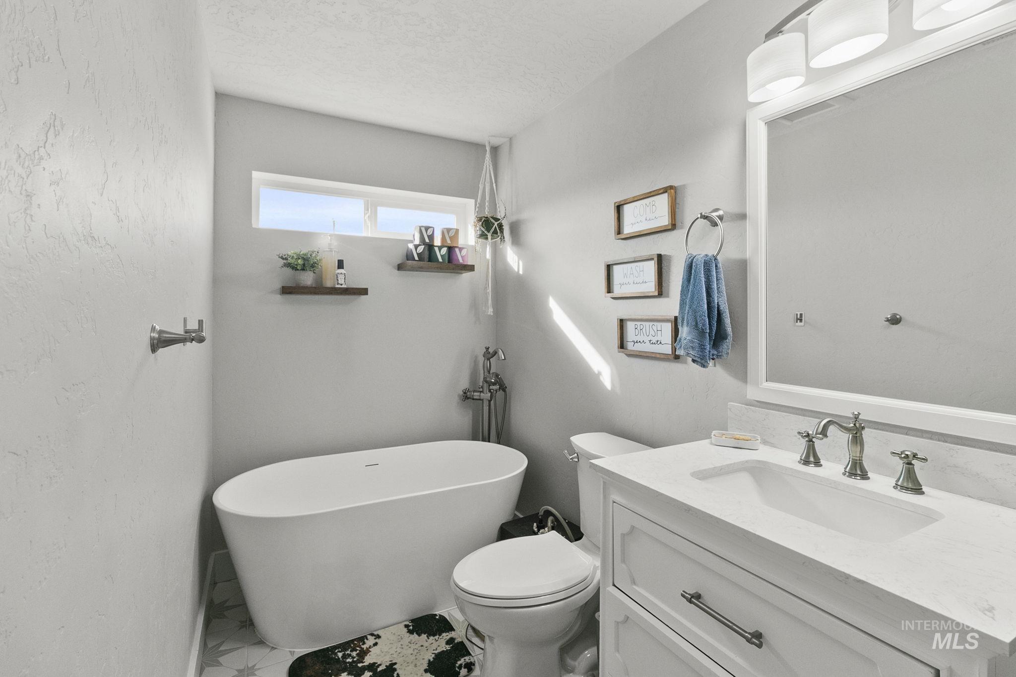 Full bath with vanity, a soaking tub, and a textured ceiling