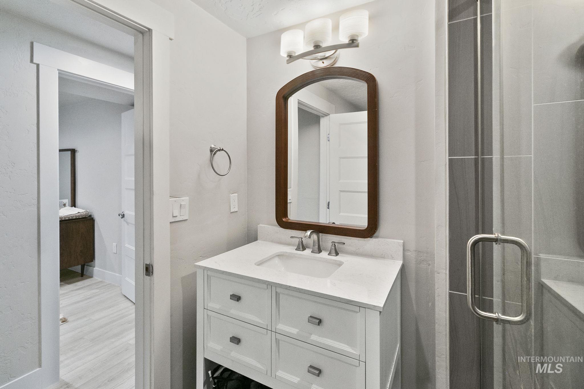 Full bath with vanity, a stall shower, and light wood-style flooring