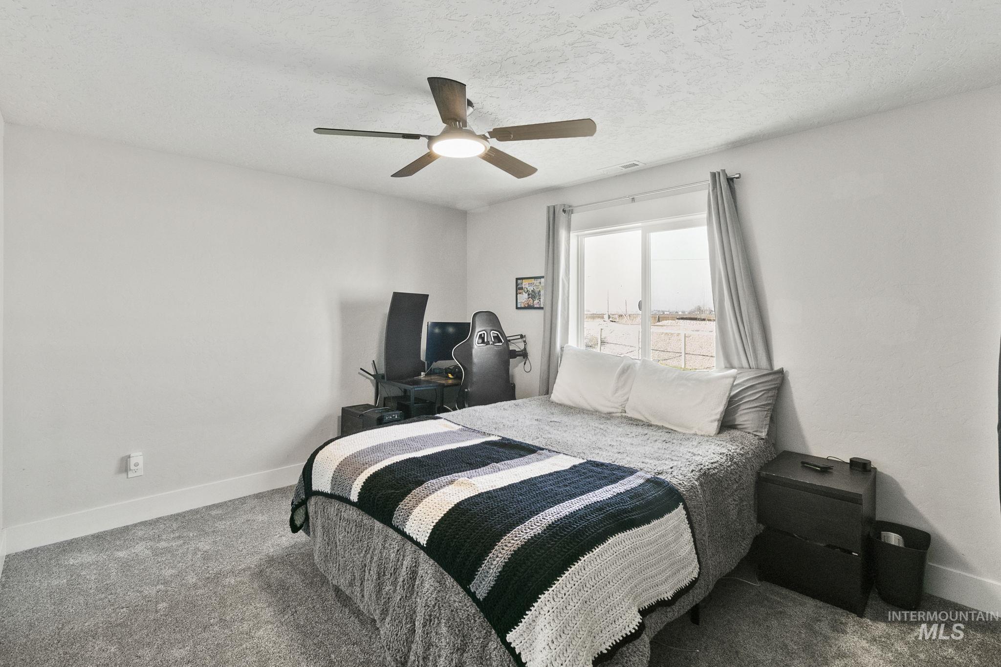 Carpeted bedroom featuring a ceiling fan and a textured ceiling